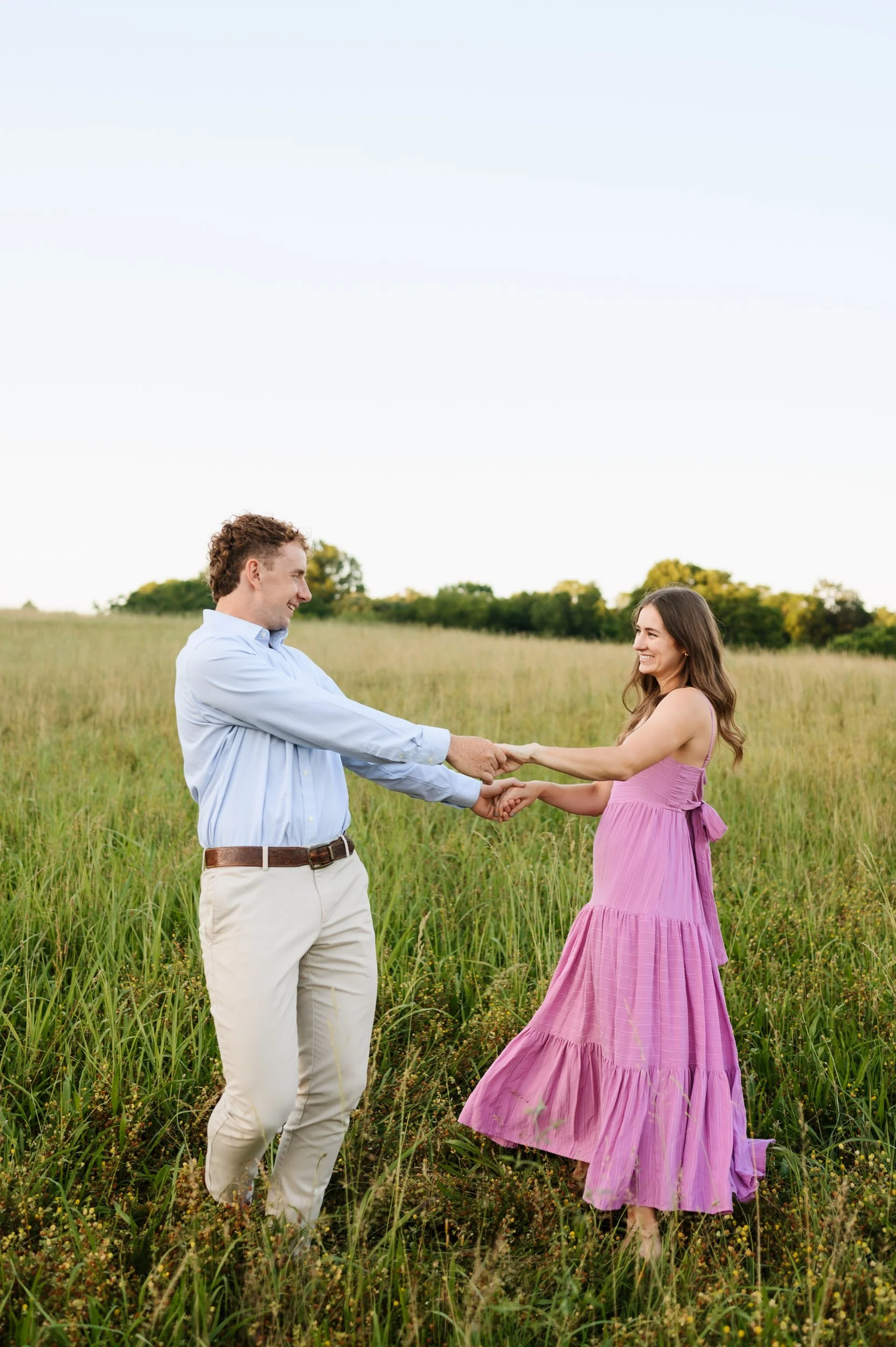 Couple holding hands spinning and laughing outdoors during Tennessee engagement session