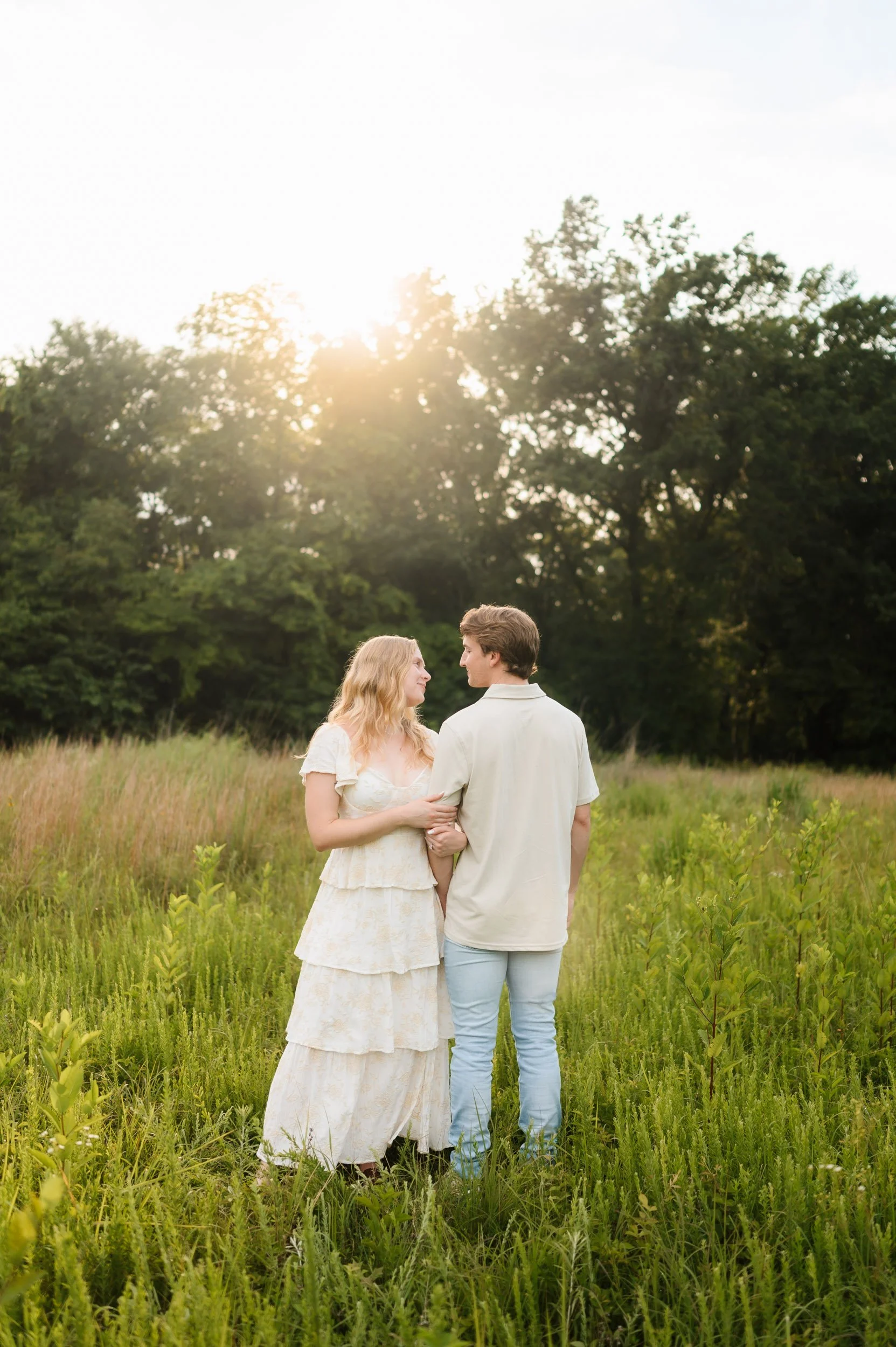 Couple embracing during engagement session in open grassy field in Murfreesboro Tennessee