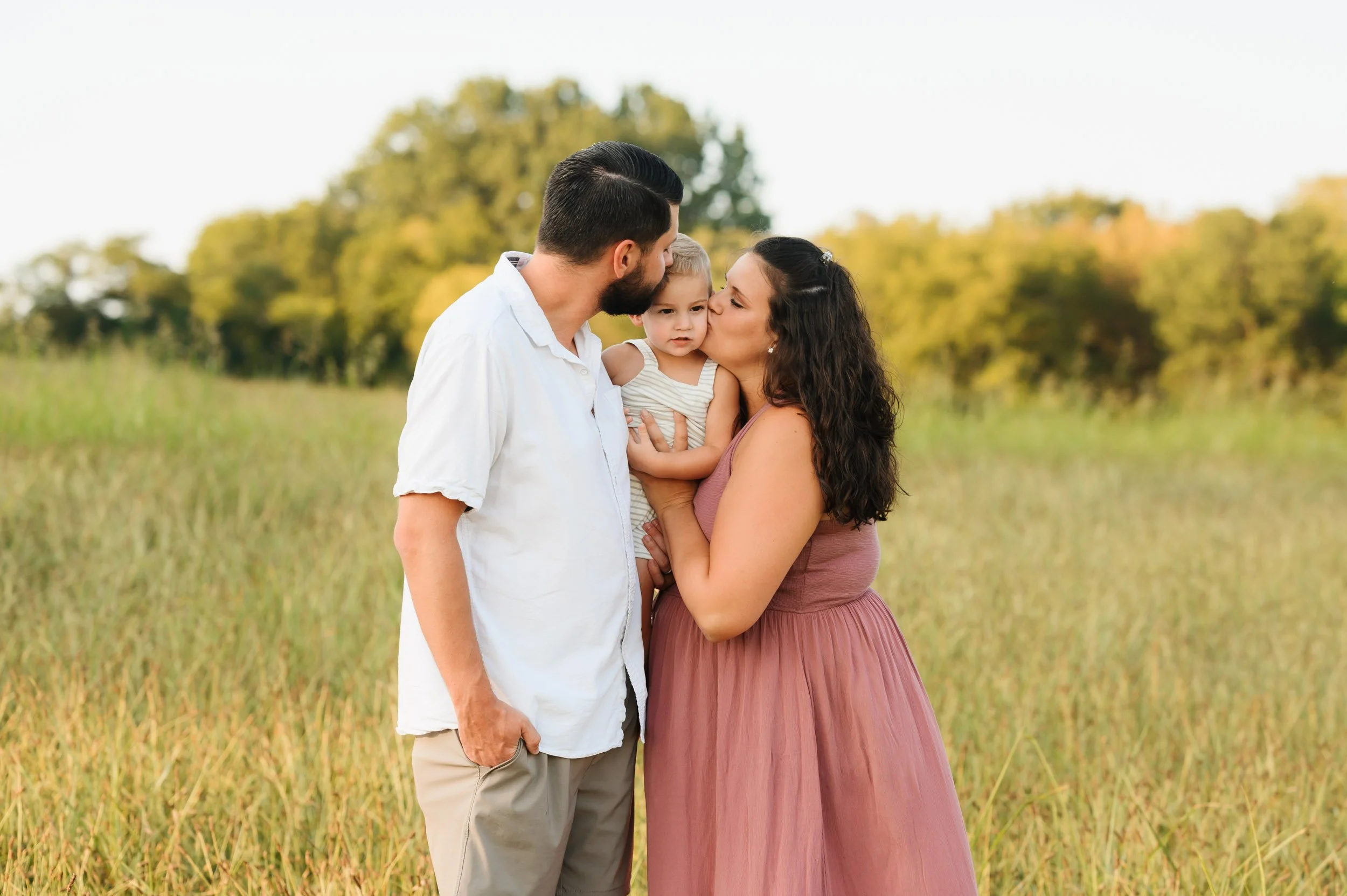 Family embracing in open field during outdoor portrait photography session