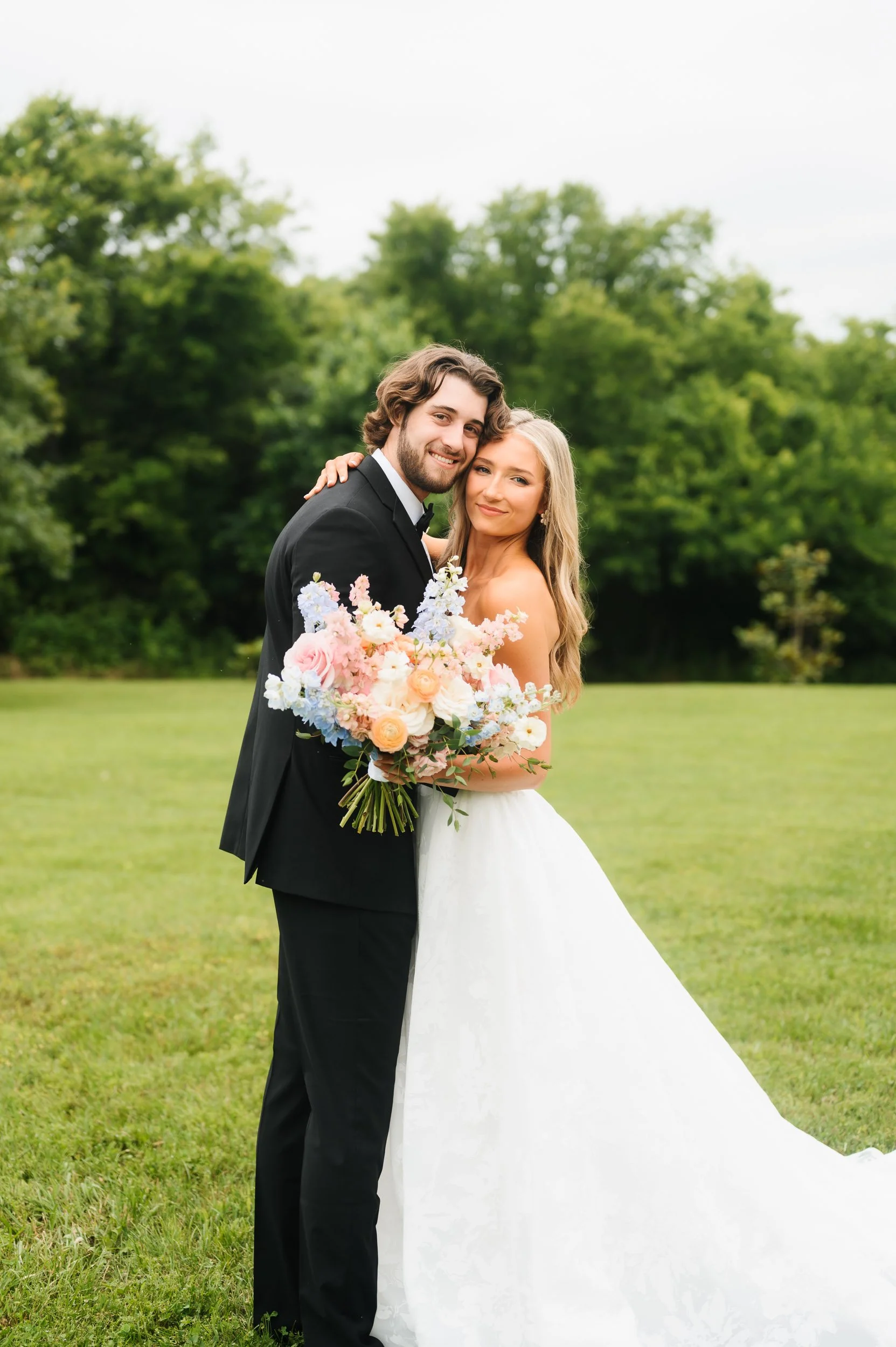 Bride and groom embracing outdoors with colorful bouquet during wedding portraits