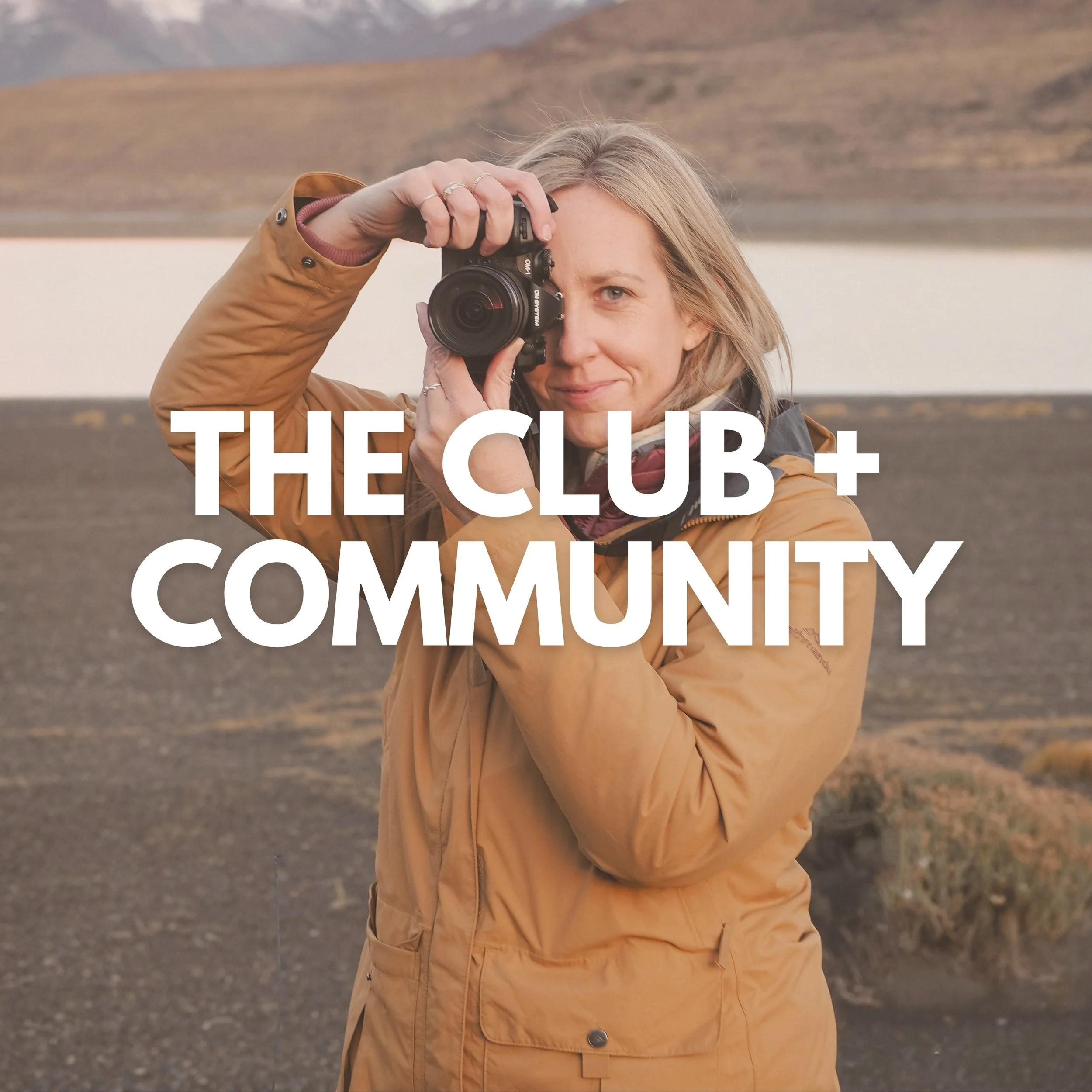 A woman in a tan jacket holding a camera up to her face, taking a picture outdoors with a landscape background of land, water, and mountains, overlaid with the text "THE CLUB + COMMUNITY".