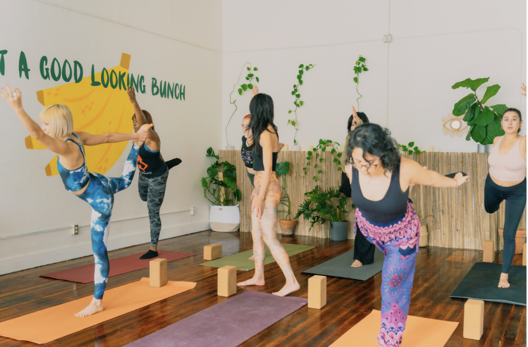 Diverse group of women practicing Ashtanga yoga. They are in dancers pose during a power vinyasa class.