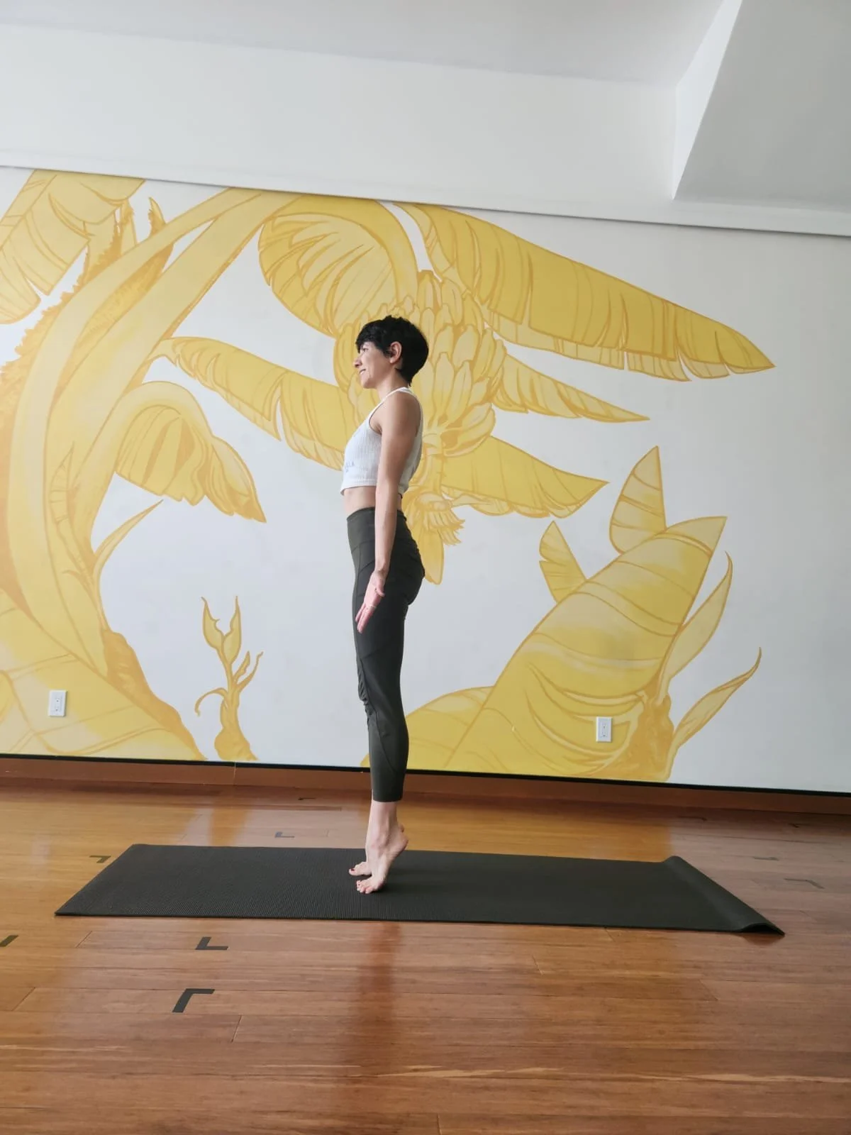 Woman with short pixie haircute standing on the balls of her feet with her heels lifted.