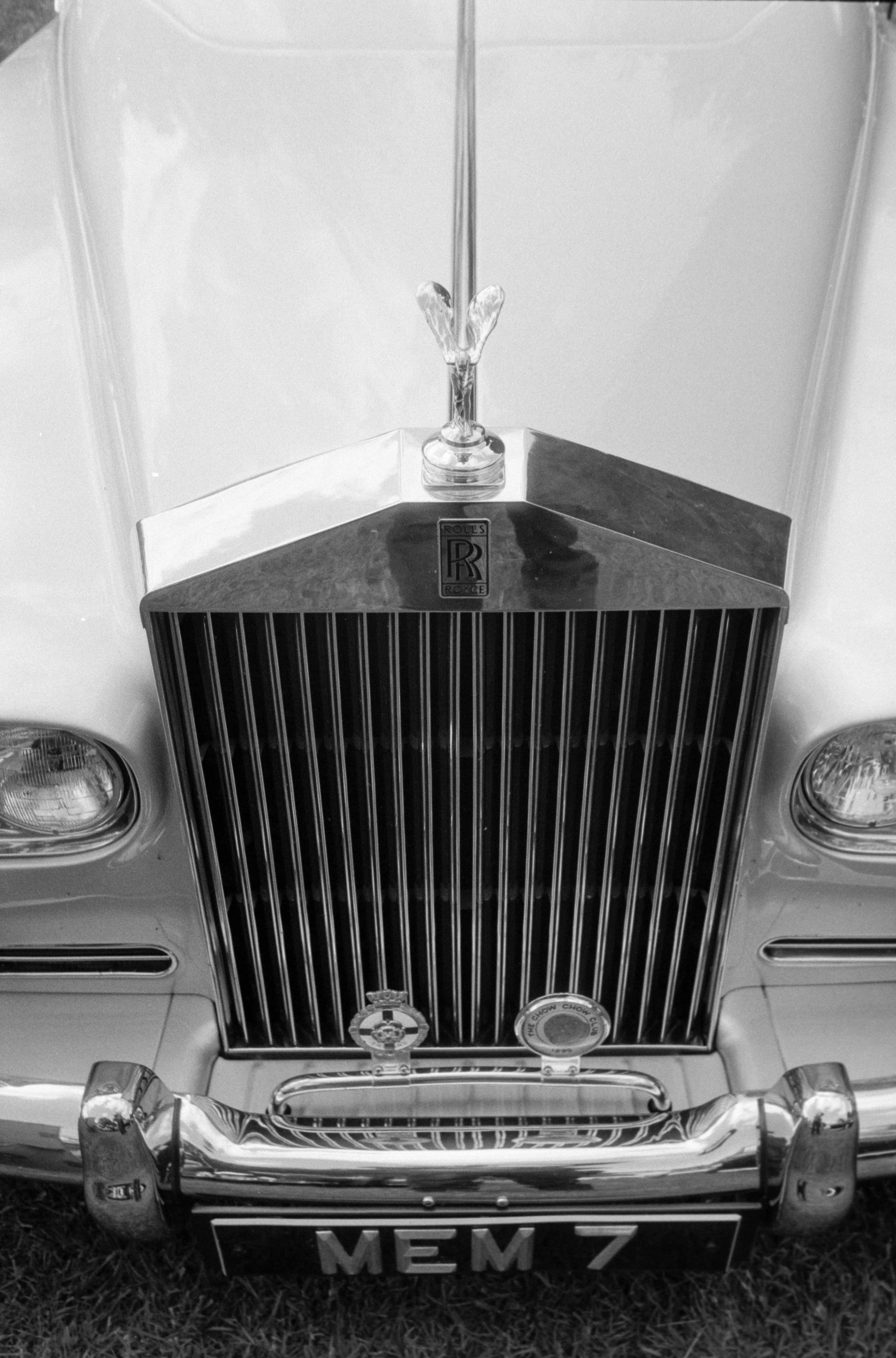 Front view of a vintage Rolls-Royce car with a decorative hood ornament, and a front license plate that reads 'MEM 7.'