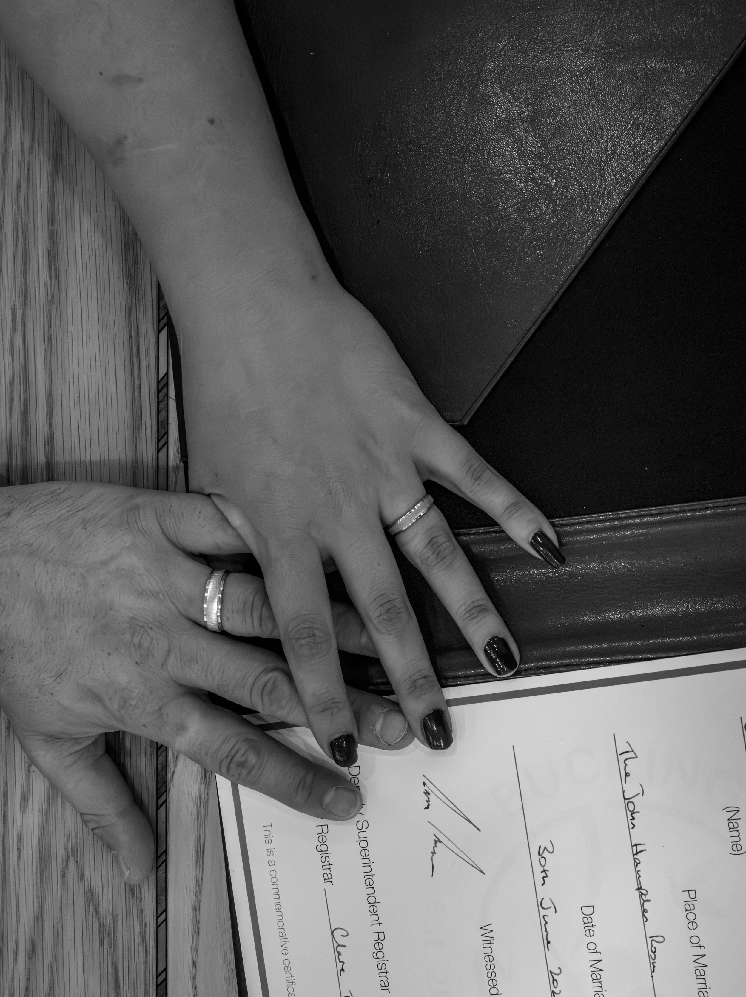 Close-up of a person's hand holding a signed document on a wooden surface.