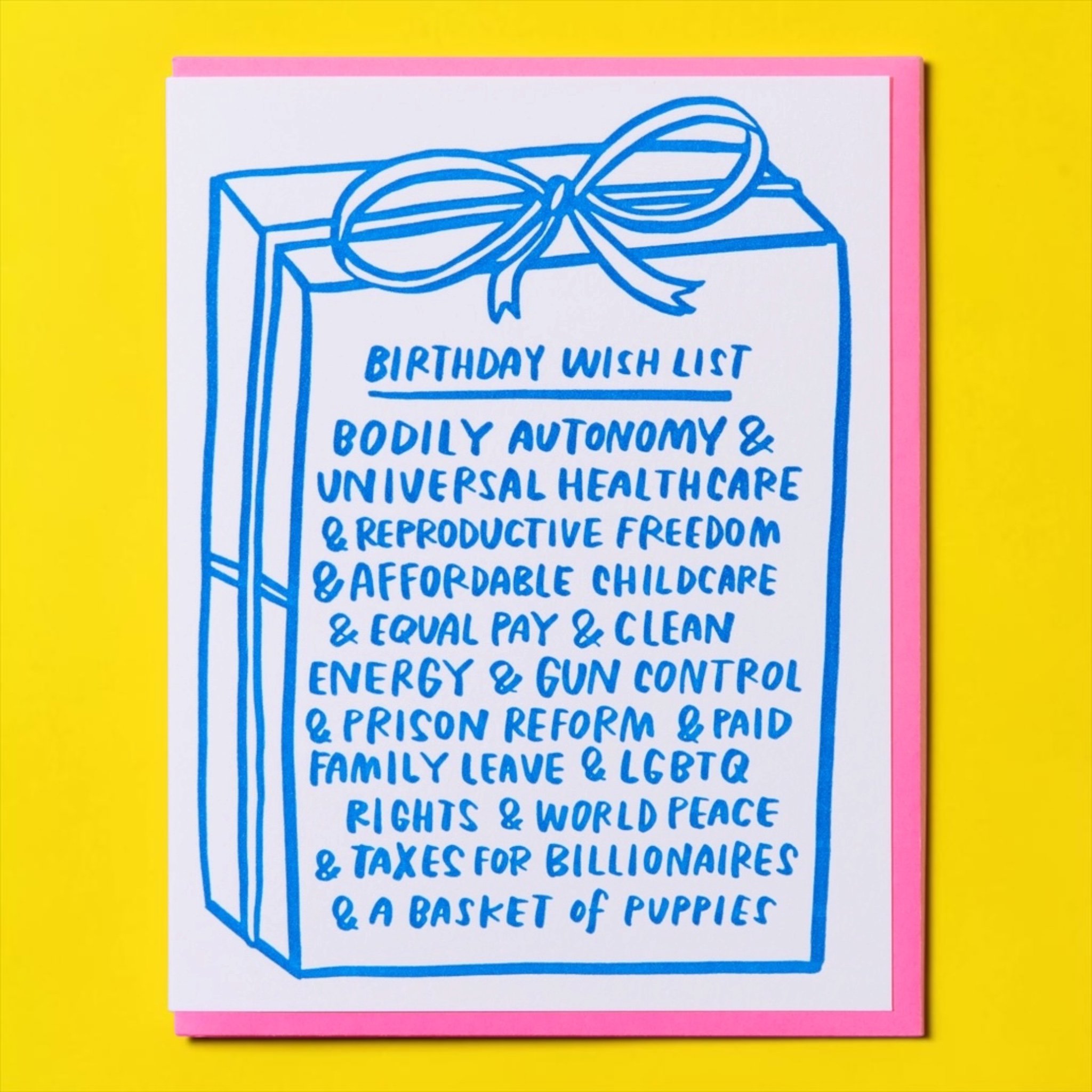 Funny feminist birthday card featuring a birthday wish list with body autonomy, universal healthcare, equal pay, LGBTQ rights, world peace and a basket of puppies, paired with a pink envelope.