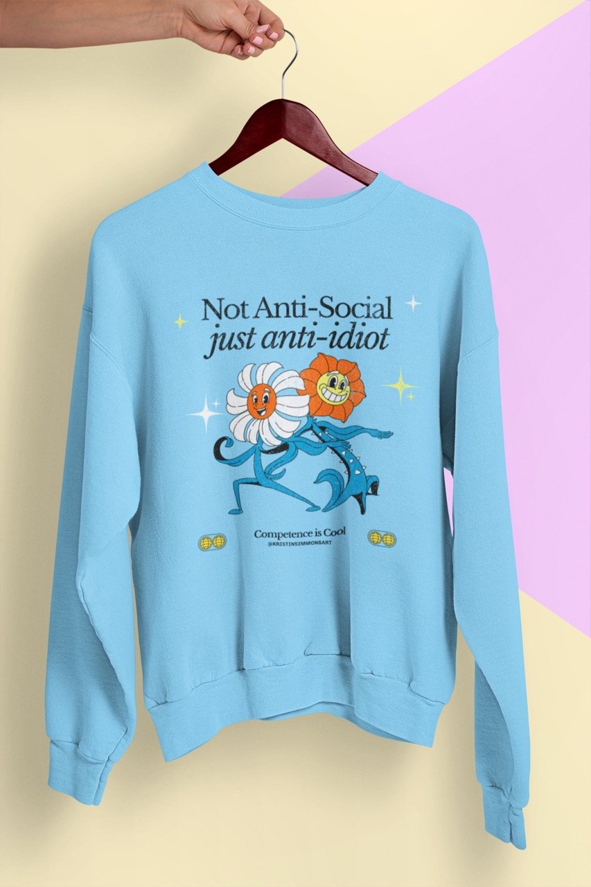 A light blue sweatshirt with playful cartoon flower design and "Not Anti-Social just anti-idiot" text.