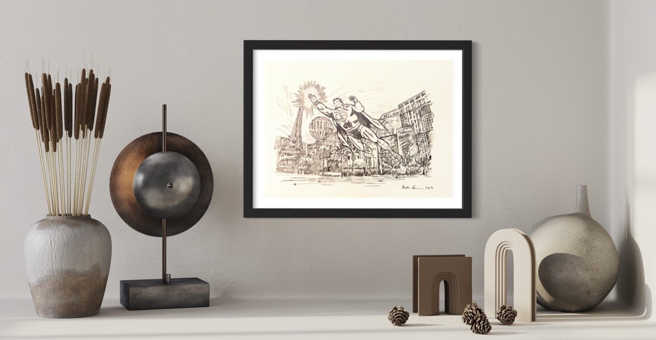 A framed sepia sketch of superman soaring above city skyscrapers by artist Kristin Simmons on a textured wall, complemented by an abstract sculpture and a rustic vase with dried flowers on a marble countertop.