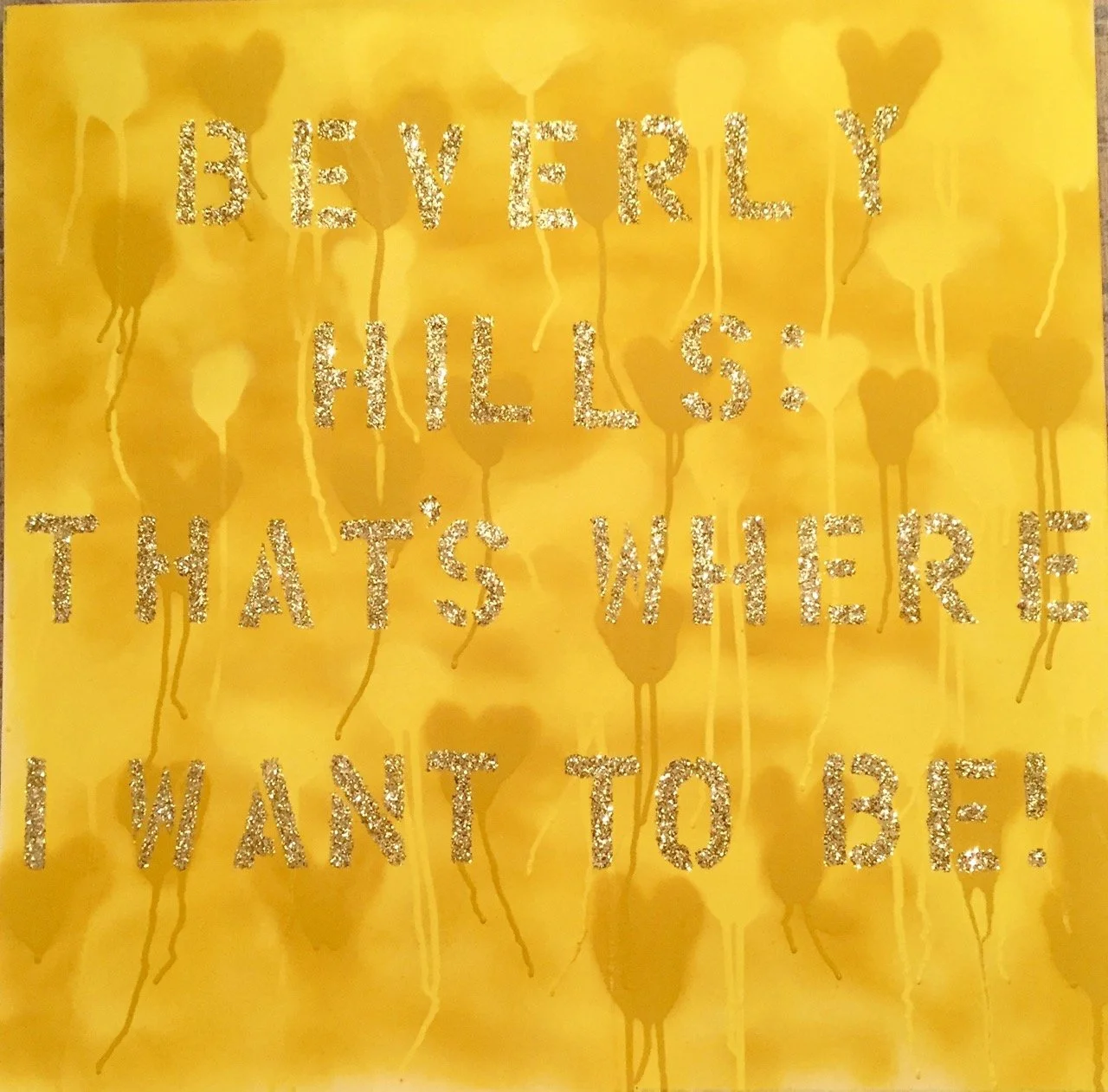 Bright yellow canvas with the text "Beverly Hills: That's Where I Want to Be!" written in glitter. The background features faint heart shapes with drips.