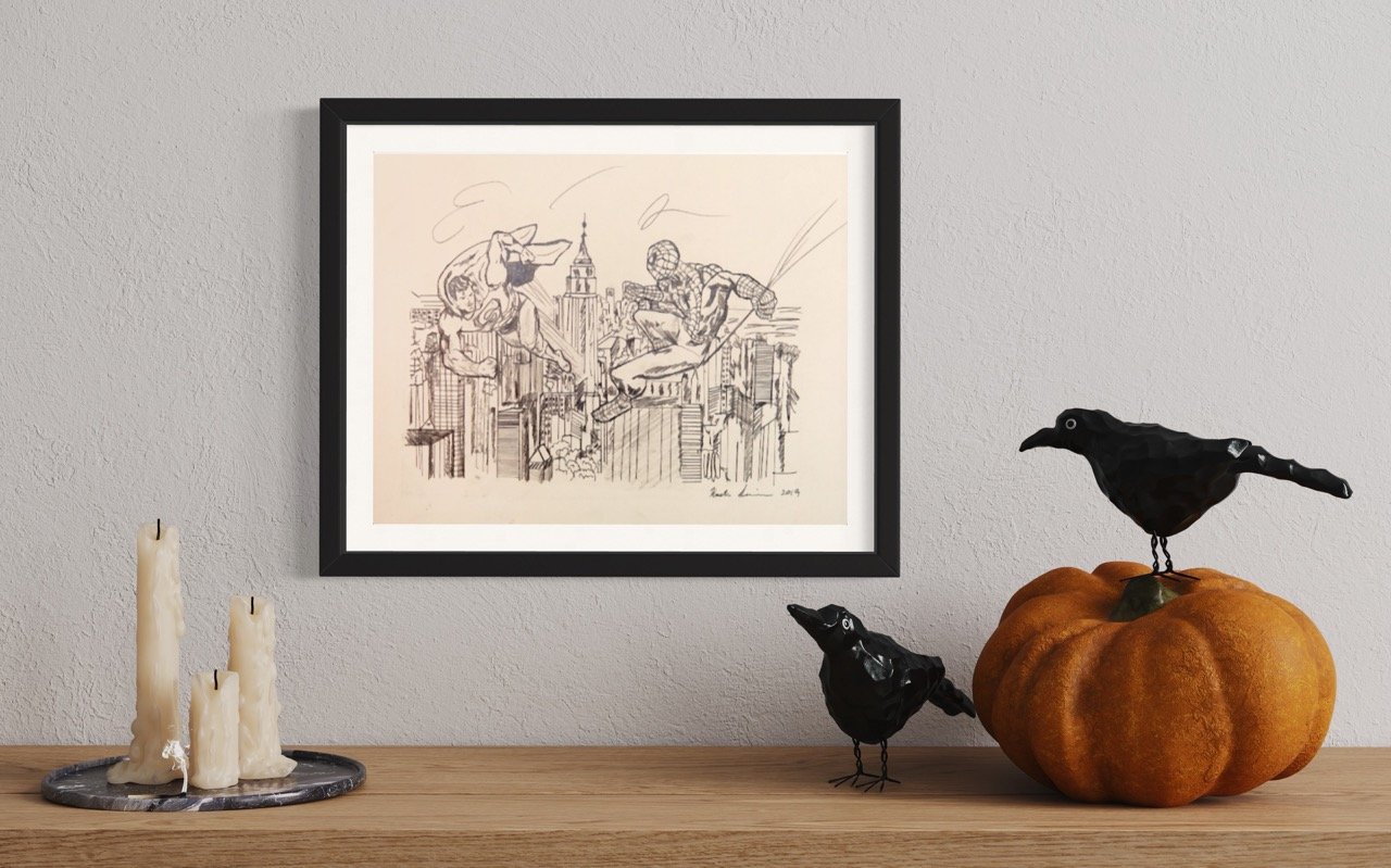 "A framed sepia-toned sketch of spiderman and superman in mid-action above a cityscape is displayed on a wall. On a wooden surface in front, melted candles on a plate, a black crow figurine, and another crow perched on a pumpkin create a Halloween-th