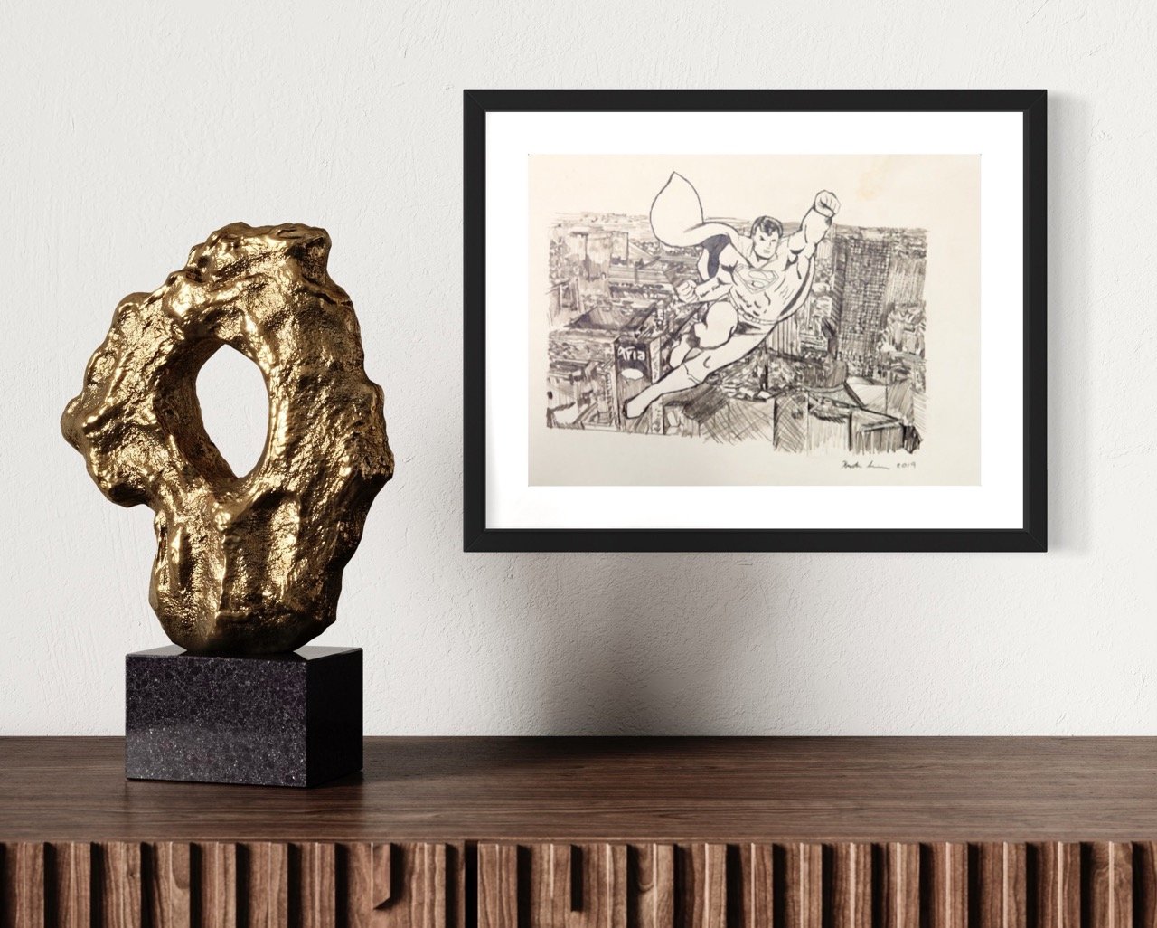 "A framed sepia sketch of superman soaring over a cityscape is prominently displayed on a wall above a sideboard, juxtaposed with a textured golden sculpture on the side."