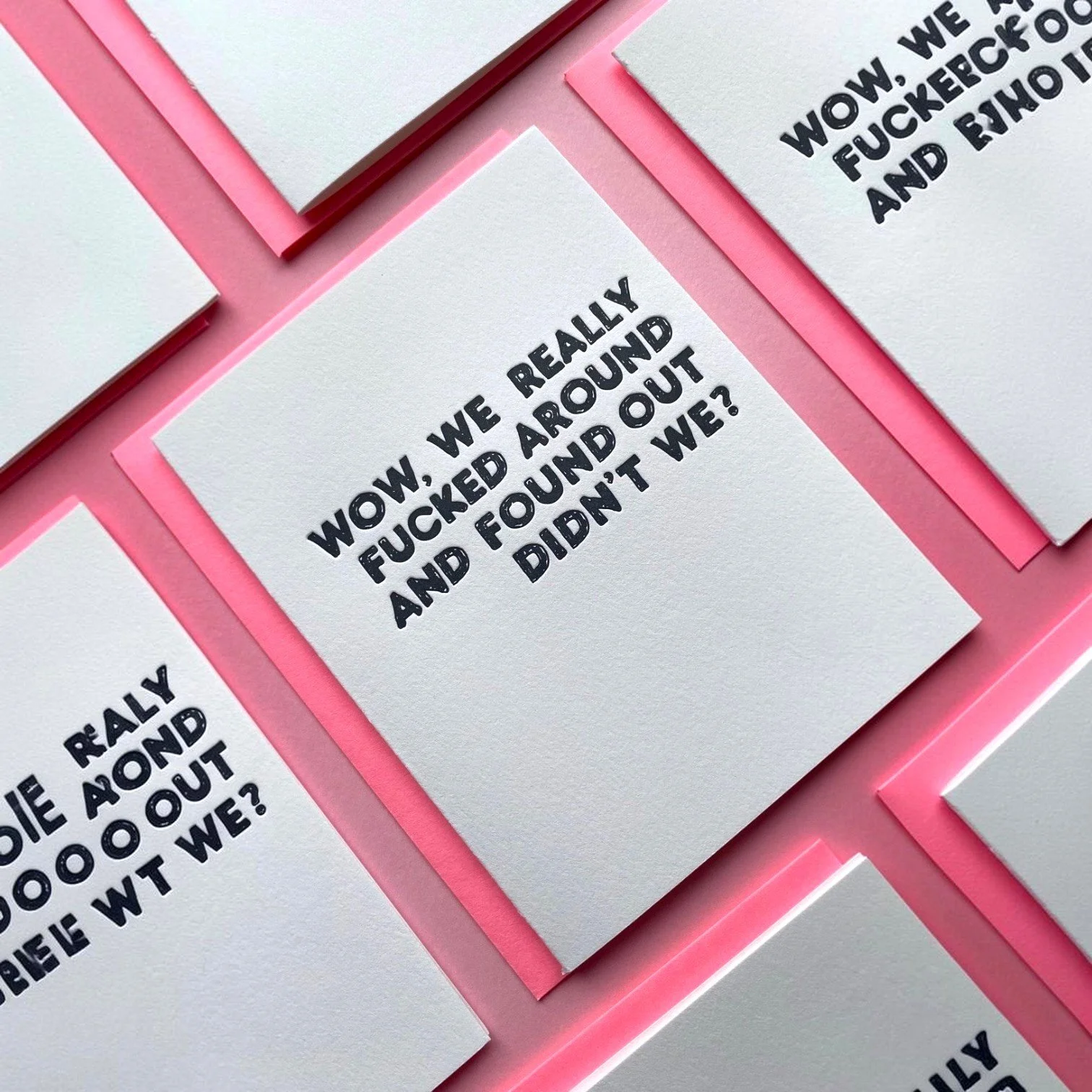 Multiple letterpress greeting cards with pink envelopes reading “Wow, we really fucked around and found out didn’t we?”