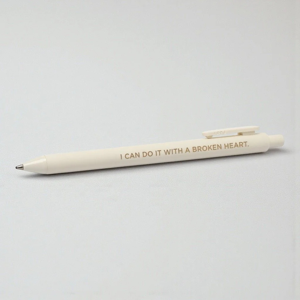 Cream-colored Taylor Swift-inspired pen with “I CAN DO IT WITH A BROKEN HEART” quote from The Tortured Poets Department era.