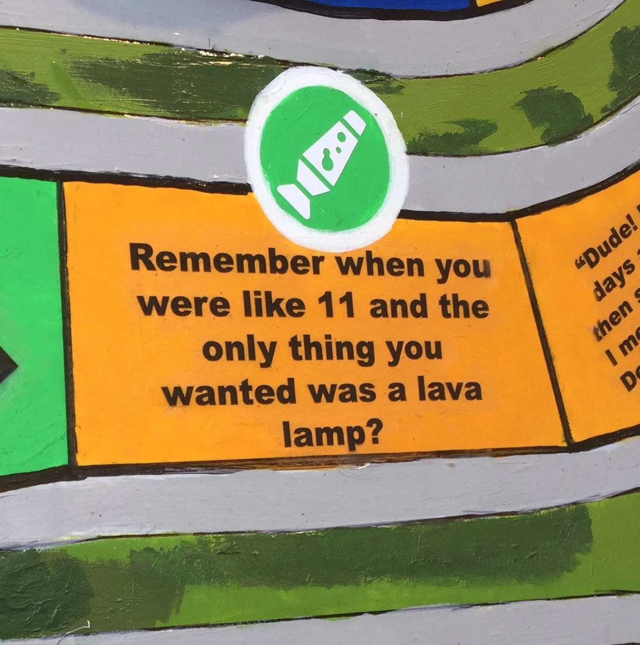 Close-up of a Game of LIFE tile with a green circle showing a lava lamp icon. Below, the text reads, "Remember when you were like 11 and the only thing you wanted was a lava lamp?"