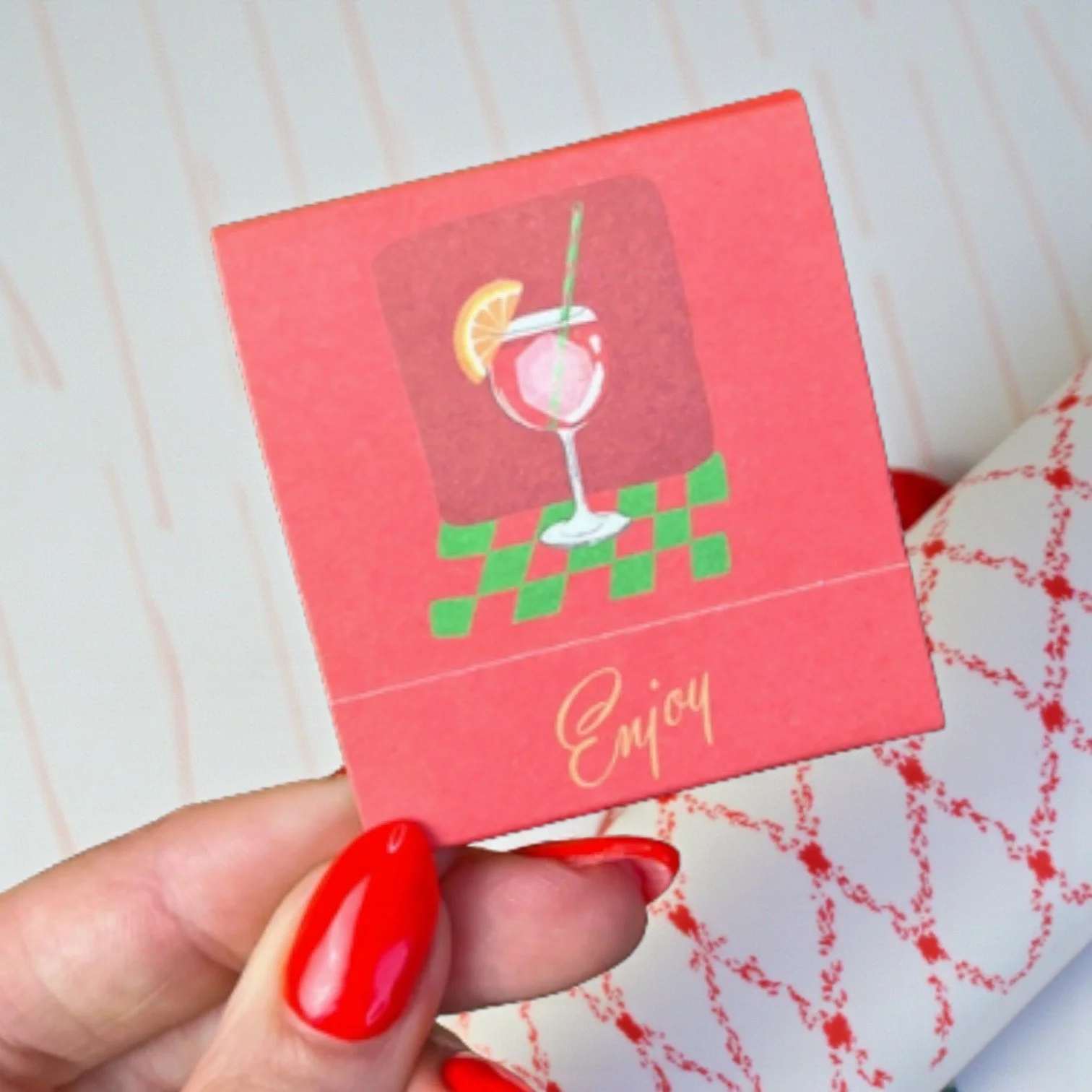 Bright orange matchbook featuring spritz illustrations and “Enjoy” text, inspired by summer cocktails.