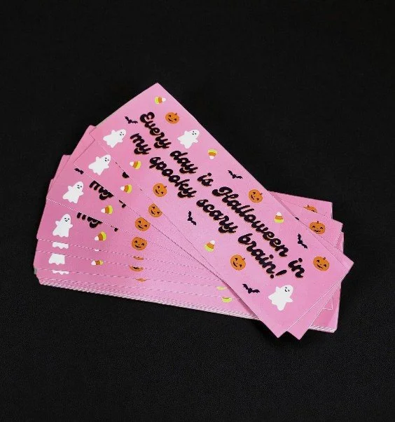 Stack of pink Halloween-themed stickers with ghosts, candy corn, bats, and pumpkins, featuring the phrase “Every day is Halloween in my spooky scary brain!”