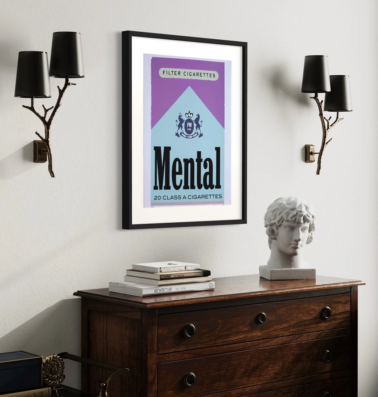 Framed silkscreen artwork by artist Kristin Simmons prominently displays the word 'Mental' with a cigarette graphic. The artwork, set against a light-colored wall, is accompanied by decorative black wall lamps and a classical bust on a wooden chest o