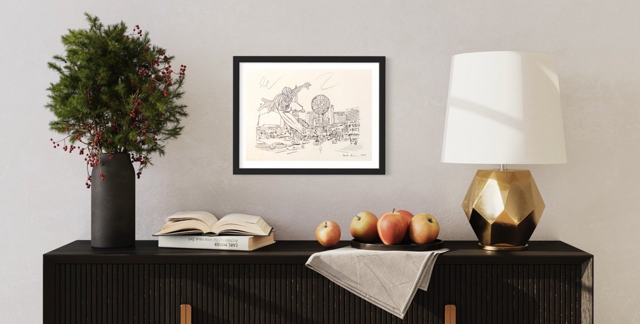 "Pencil drawing of Spiderman in action against the Las Vegas sklyine as a backdrop, centered on a wall above a black sideboard with a vibrant green plant, a stack of apples, and a geometric gold lamp."