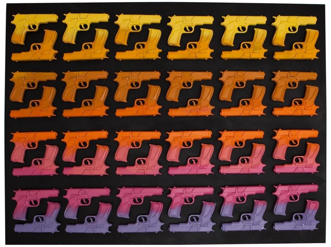 A grid of toy guns displayed on a black background, transitioning in color from yellow at the top to purple at the bottom. The guns are arranged in neat rows, creating a gradient effect.