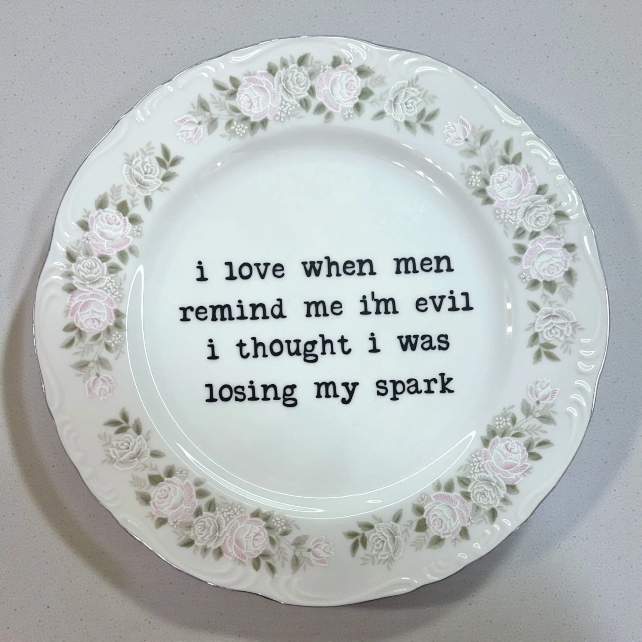 Porcelain plate with floral edge and bold quote about men, evil energy, and inner spark.