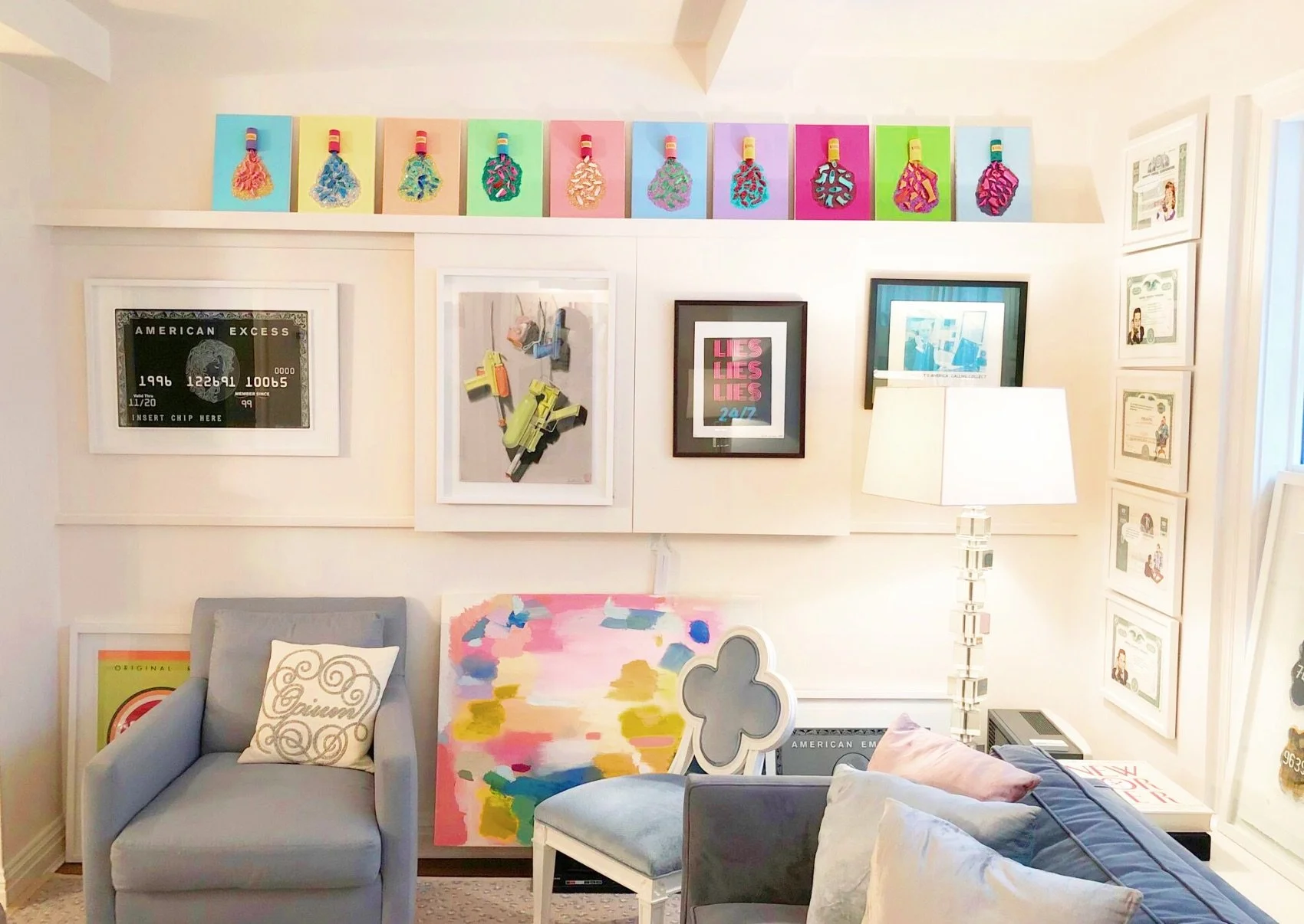 Ten bright mini canvas' with pill bottles spilling out gllitter and barbie shoes hanging on a living room wall.