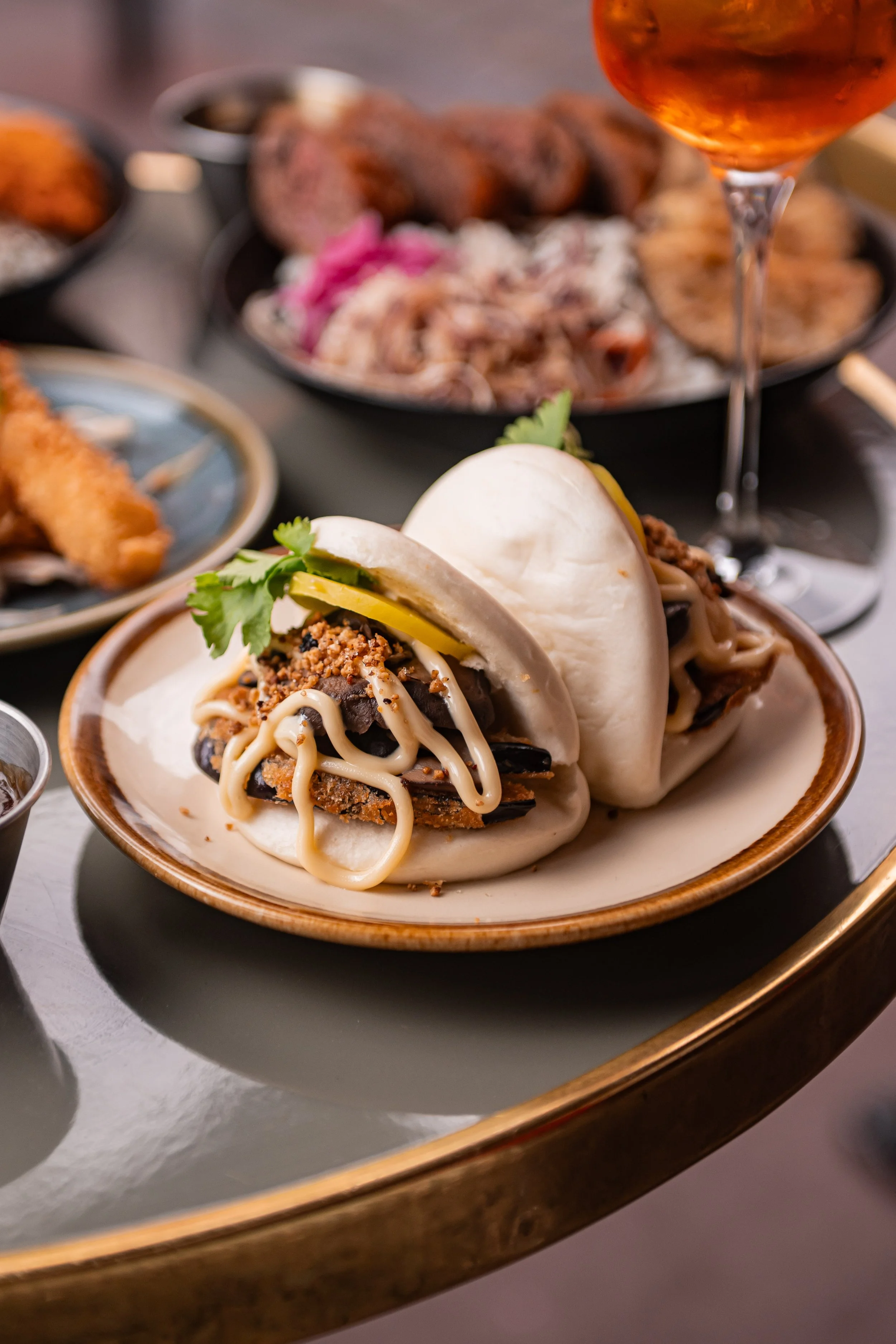 Bao bun Bao House garni de viande et sauce, servi dans une assiette dorée à Toulouse