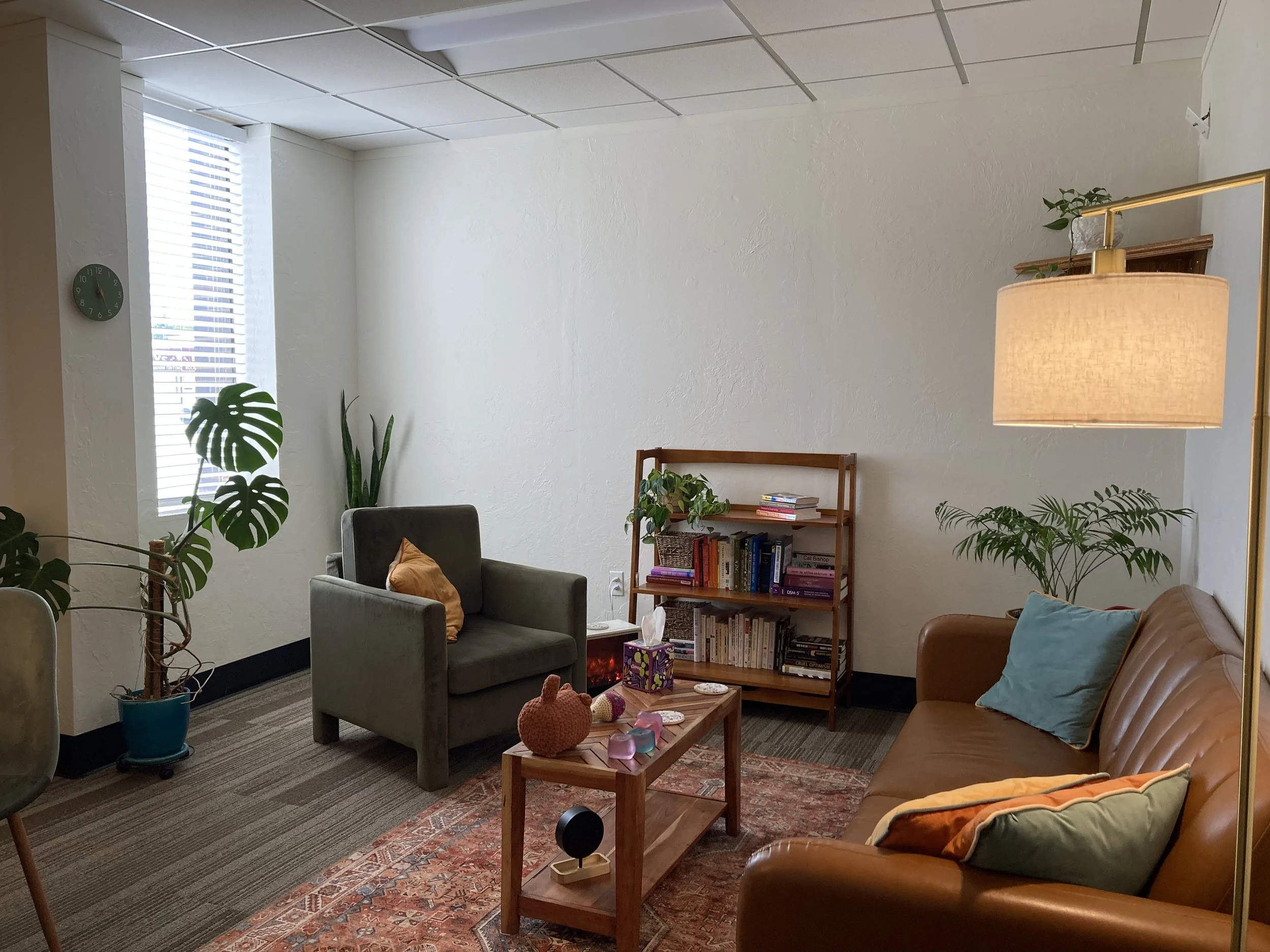 Warm living room style counseling space reflecting the compassionate, relational therapy approach at Here We Are Therapy.