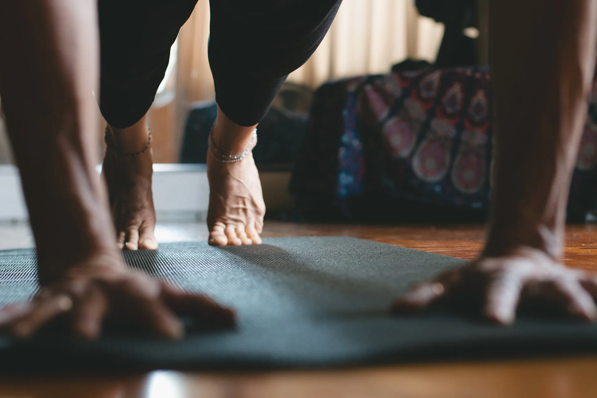 Person practicing yoga in downward dog pose on a yoga mat indoors.