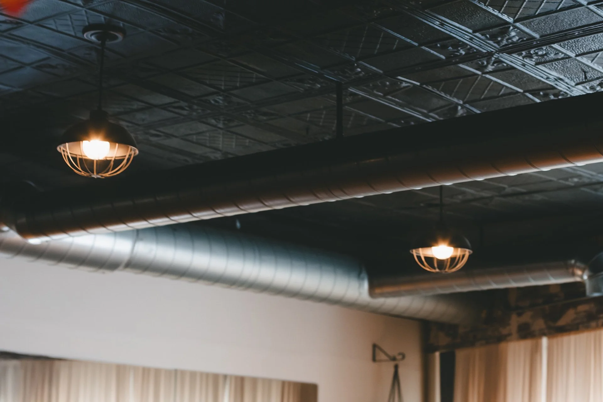 Industrial-style ceiling with exposed ductwork and hanging light fixtures.