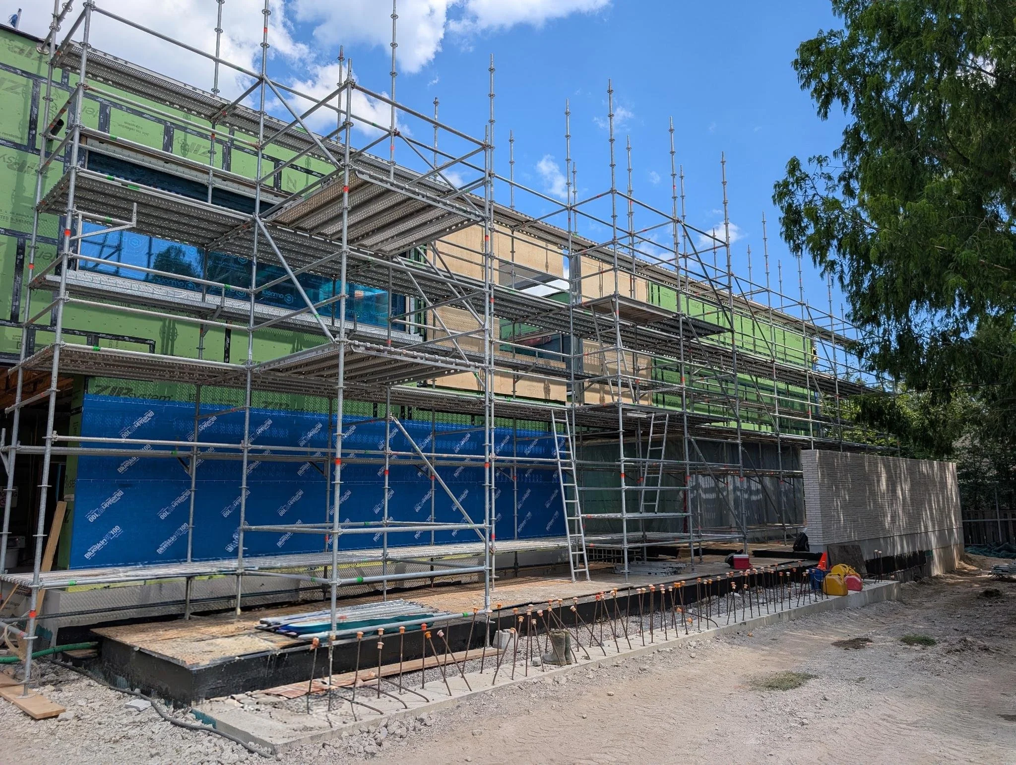 Large engineered scaffold construction on a building under construction with tarps and concrete pouring