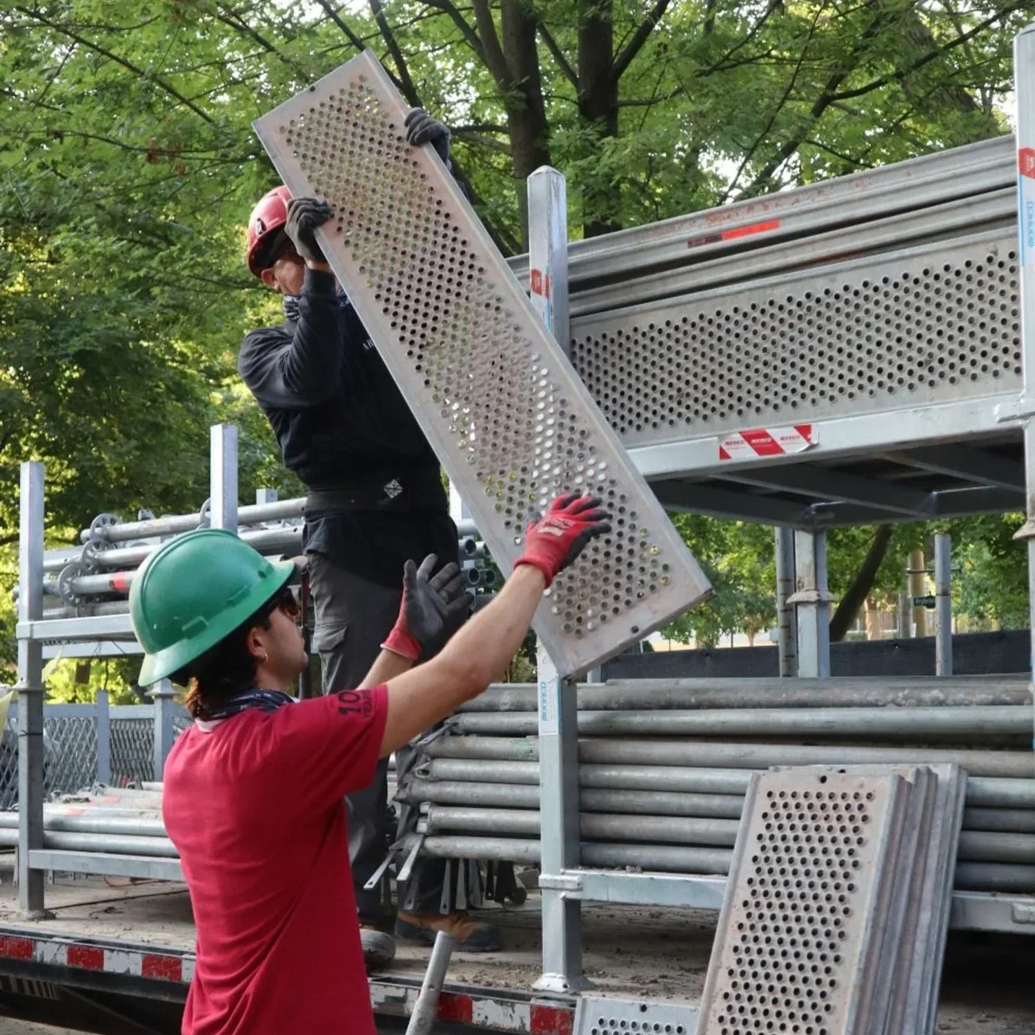 Scaffold crew workers loading modular system scaffolding pieces into a truck