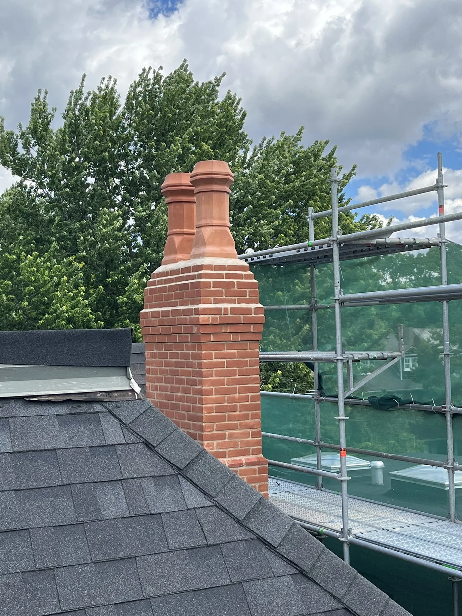 Restored red brick chimney with access scaffolding on roof of Toronto house
