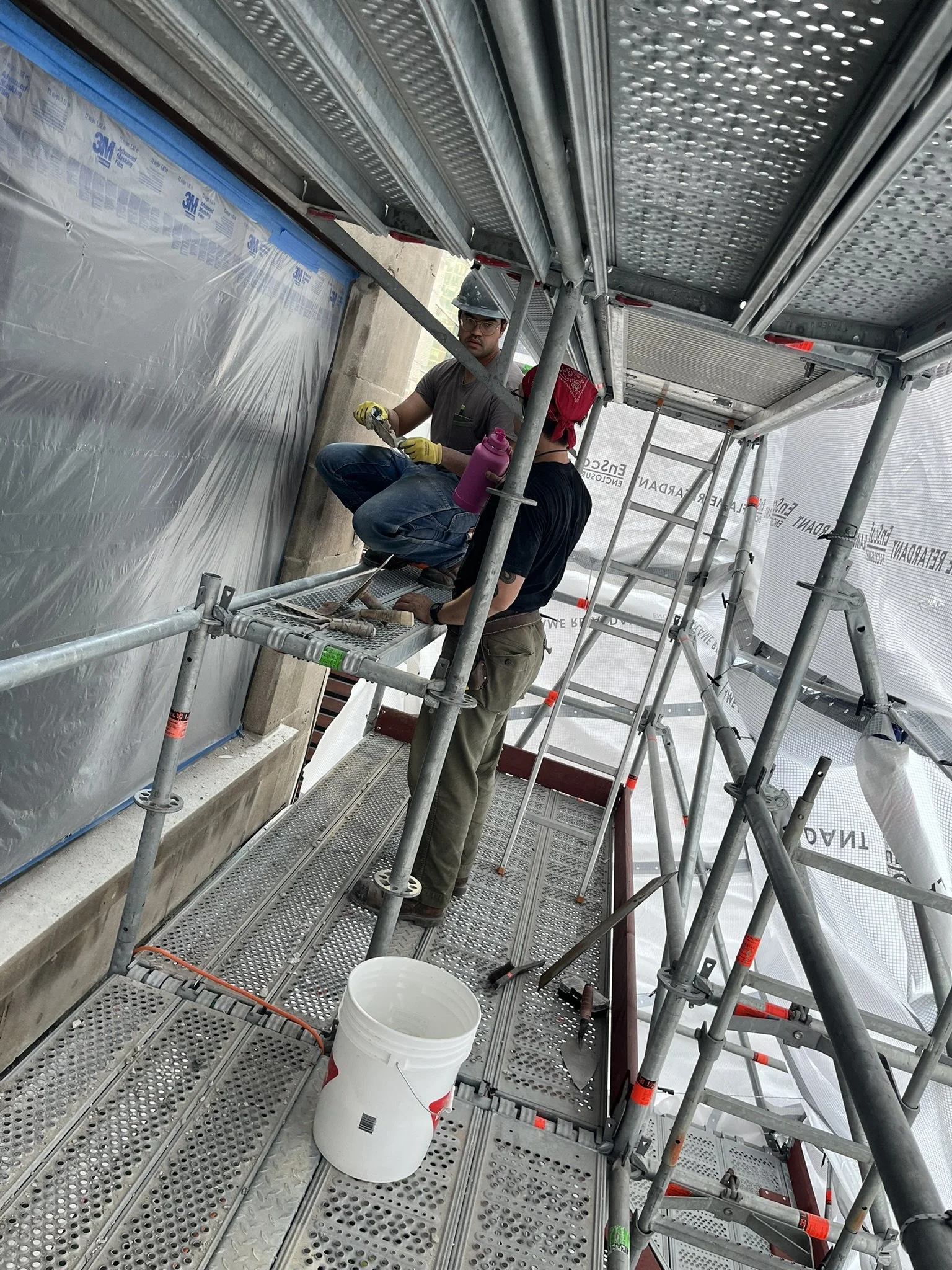 Two masons working on building restoration on scaffolding in downtown Toronto