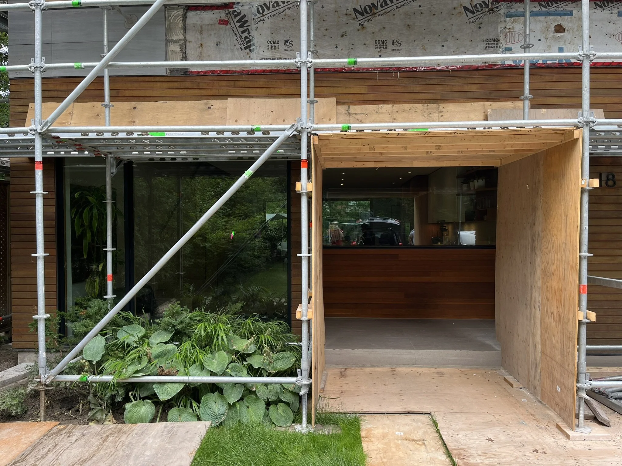 Scaffolding at ground level with plywood hoarding, mud sills and base plates