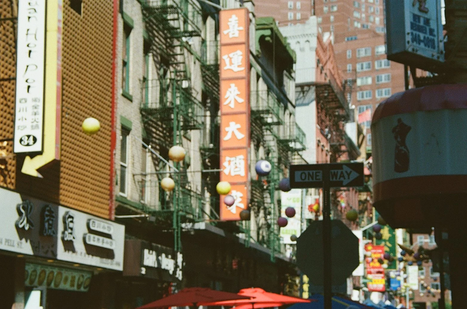 Una calle en Chinatown con signos en chino, faroles y edificios en el fondo.