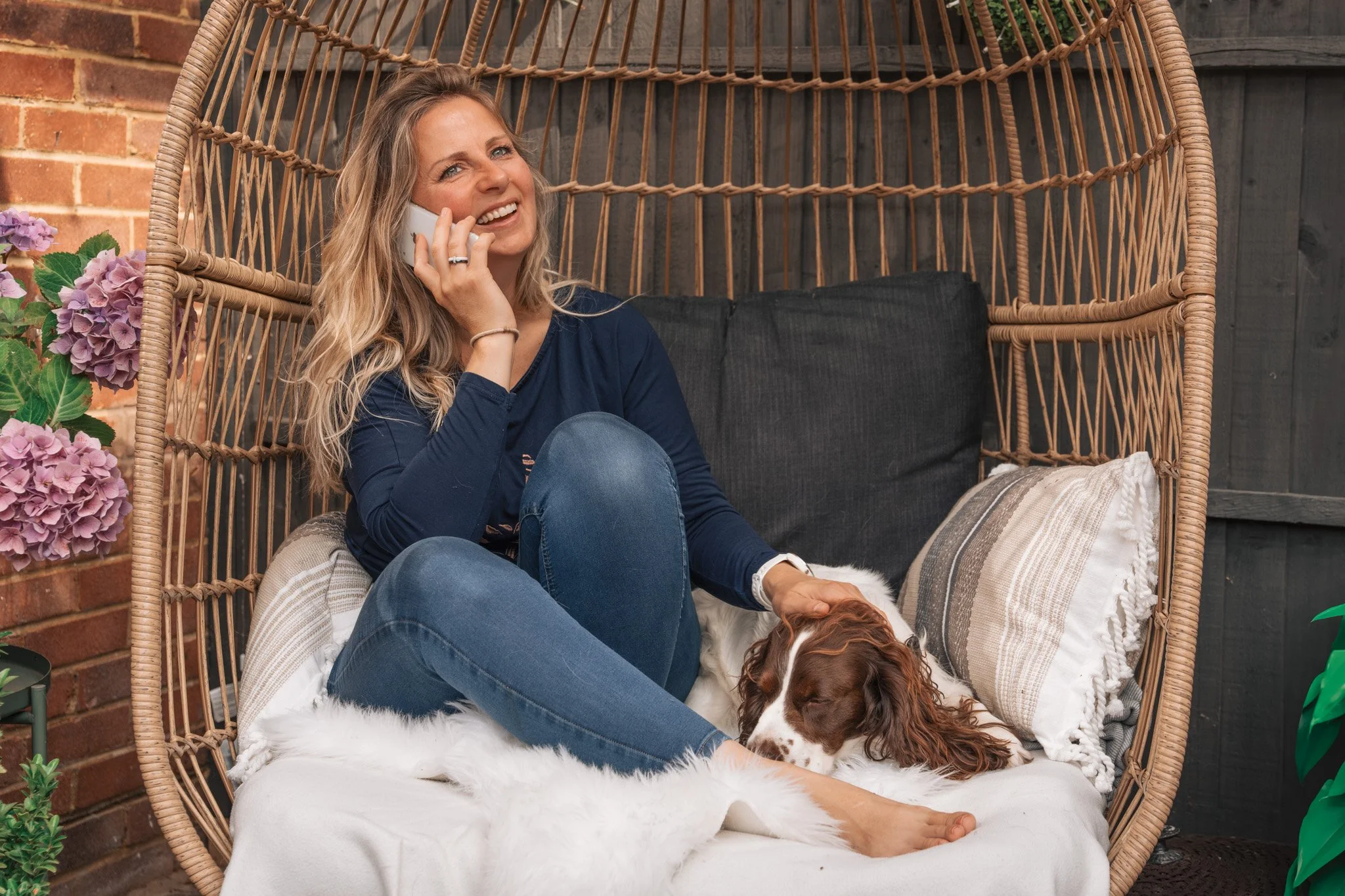Woman smiling on the phone with her Cocker Spaniel asleep beside her, speaking to KnightPics Photography about her photoshoot
