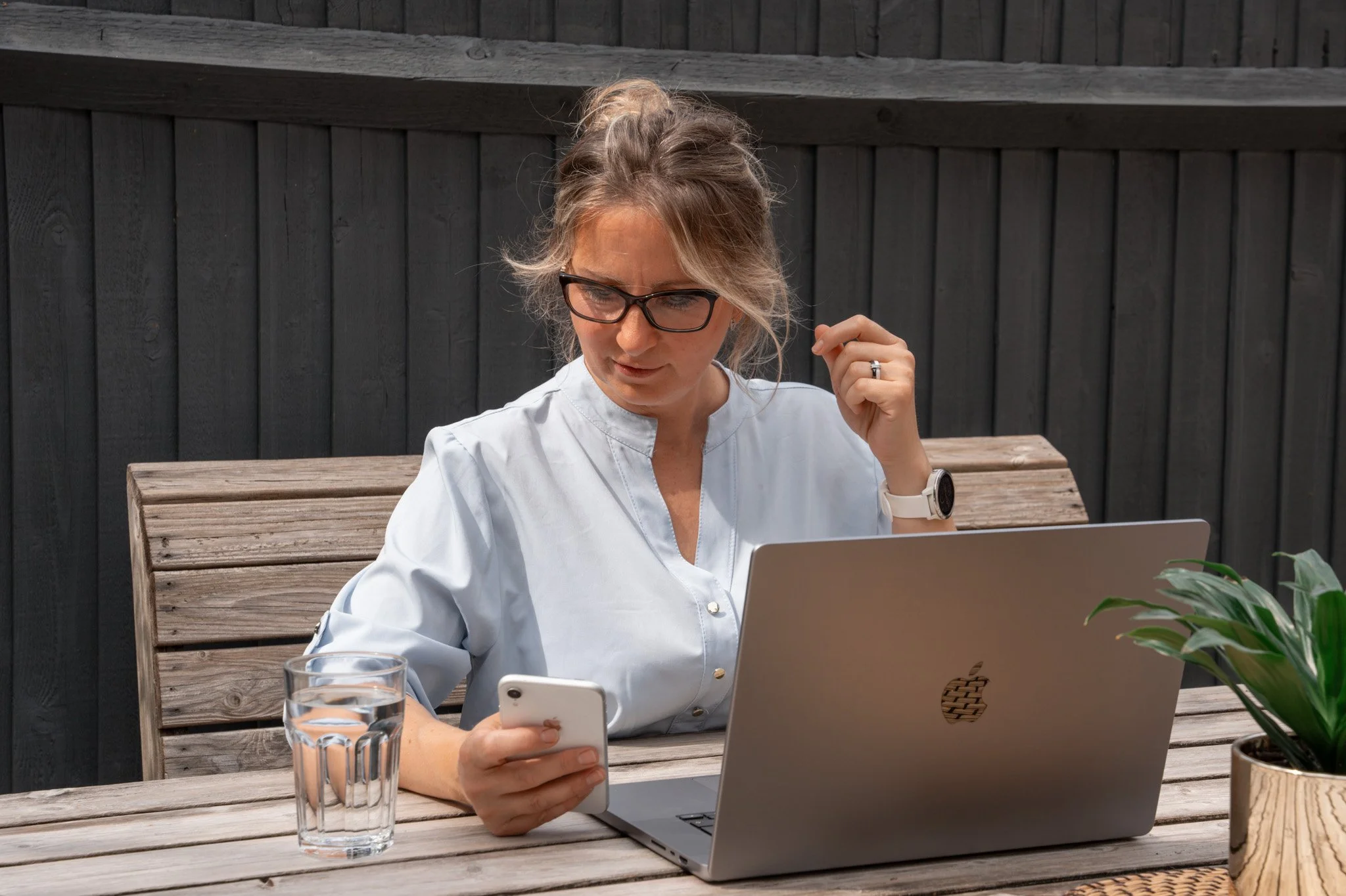 Woman using her phone and laptop to contact KnightPics Photography about a pet photoshoot