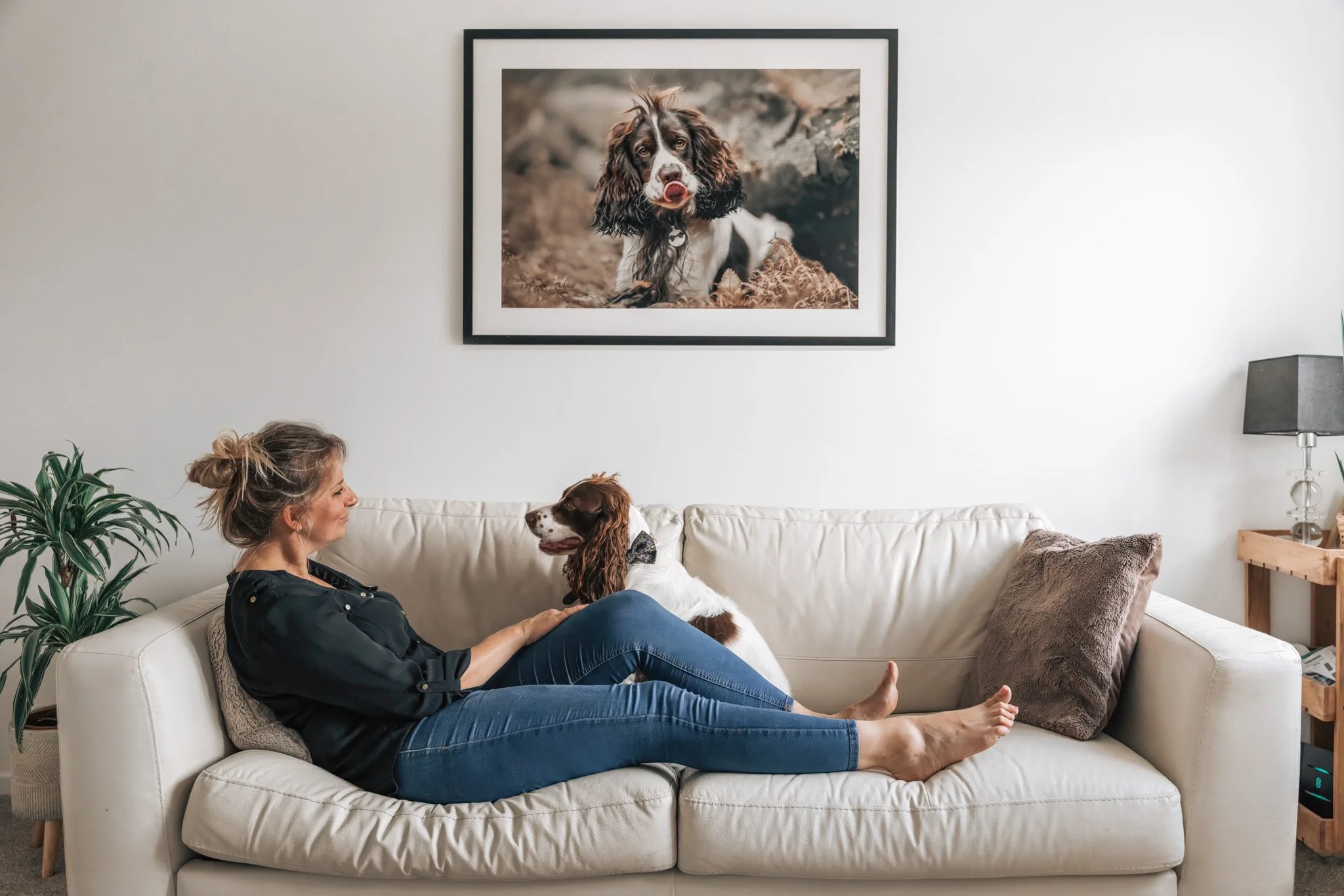 Woman and her Cocker Spaniel lovingly looking at each other with a framed pet portrait displayed above them, delivered by KnightPics Photography
