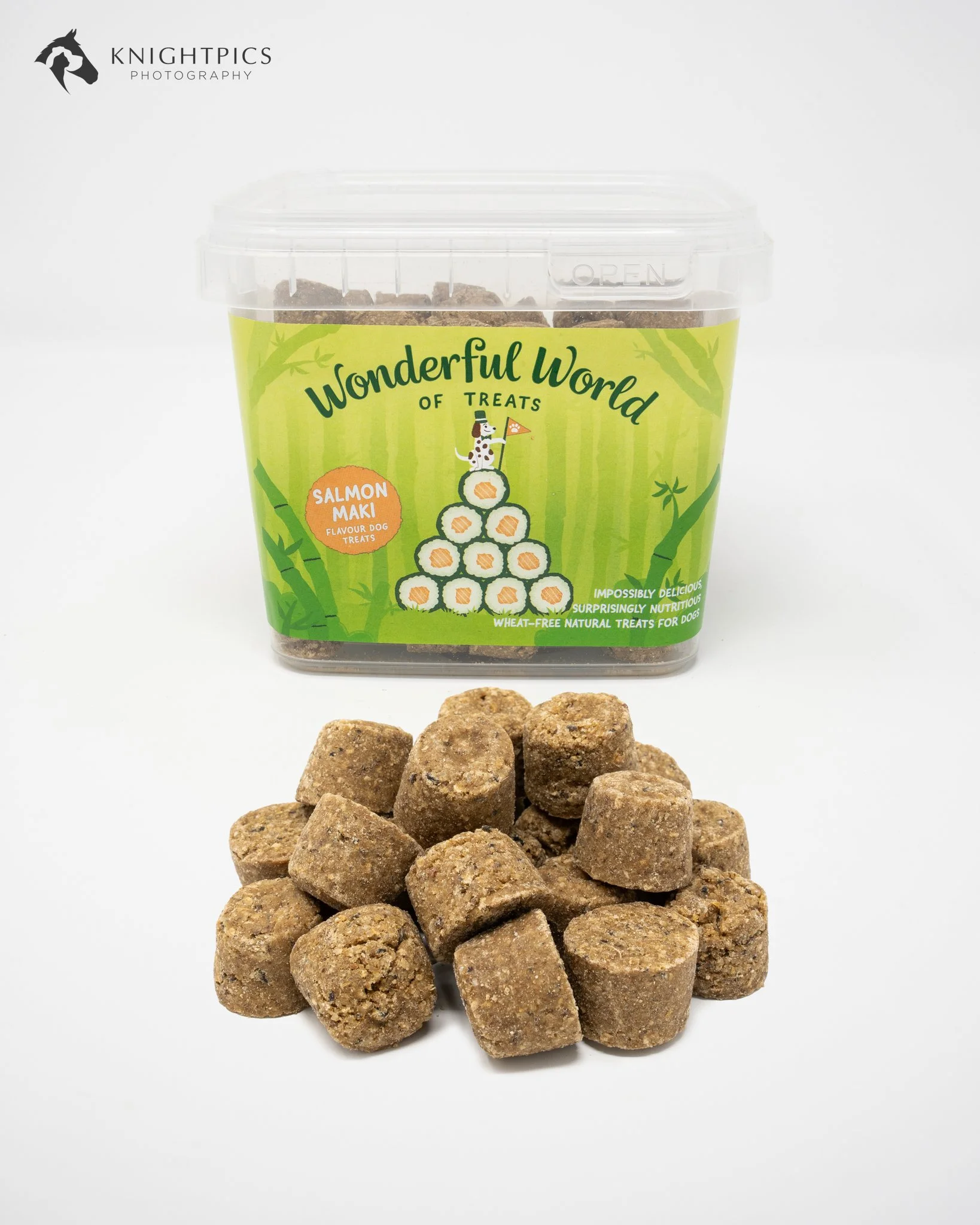 Professional commercial product photography featuring a tub of Salmon Maki flavour dog treats from The Wonderful World of Treats, with individual treats arranged in the foreground. Photographed against a clean white background to highlight the colour
