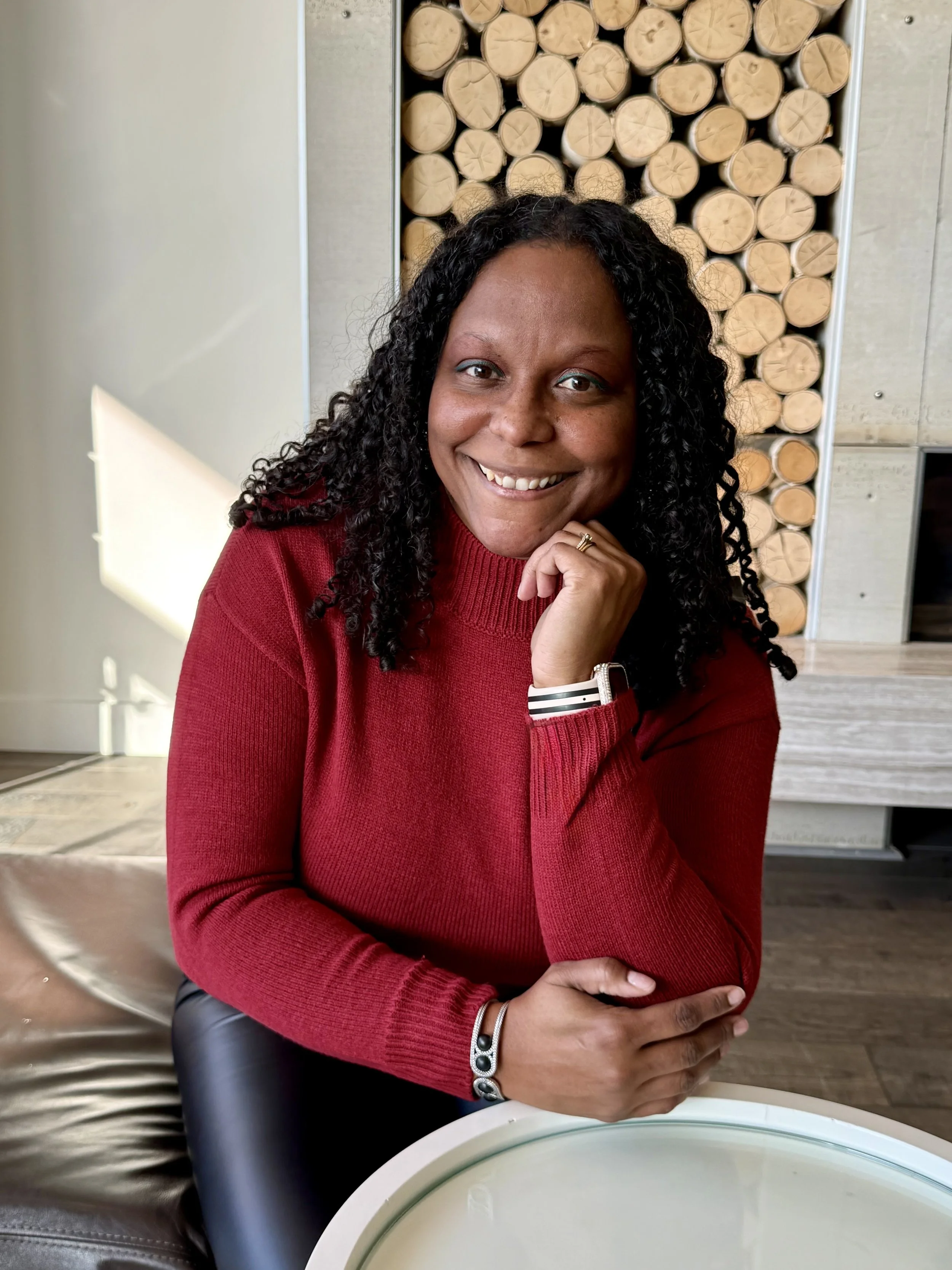 Photo of Shanta Sweet Mancebo in a red shirt and leaning on a chair.