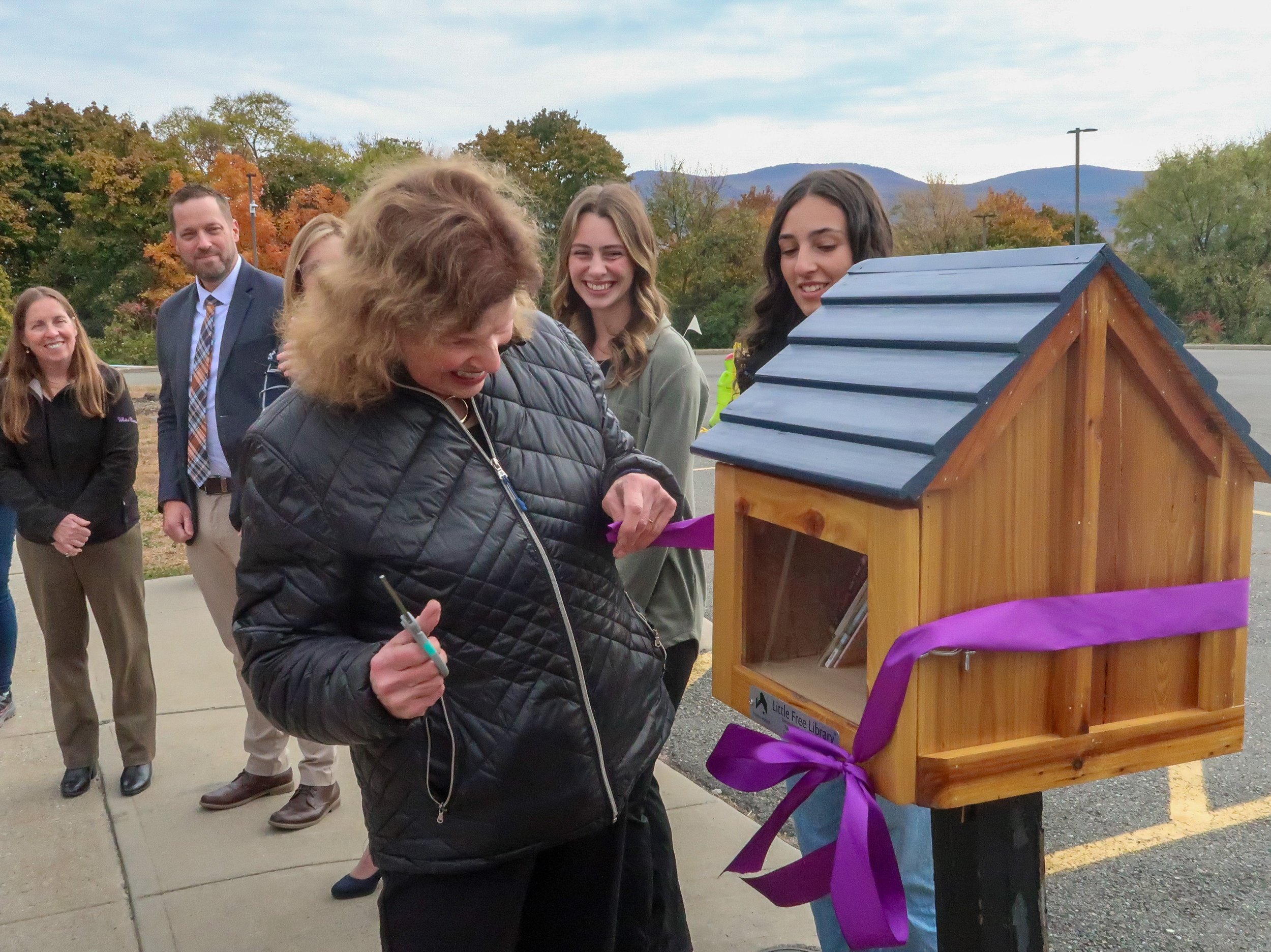   Sonya Abbye-Taylor, associate professor of Education, Chair of the Division of Education, and Kappa Delta Pi counselor at Mount Saint Mary College, cuts the ribbon for the Little Free Library at Bishop Dunn Memorial School.  