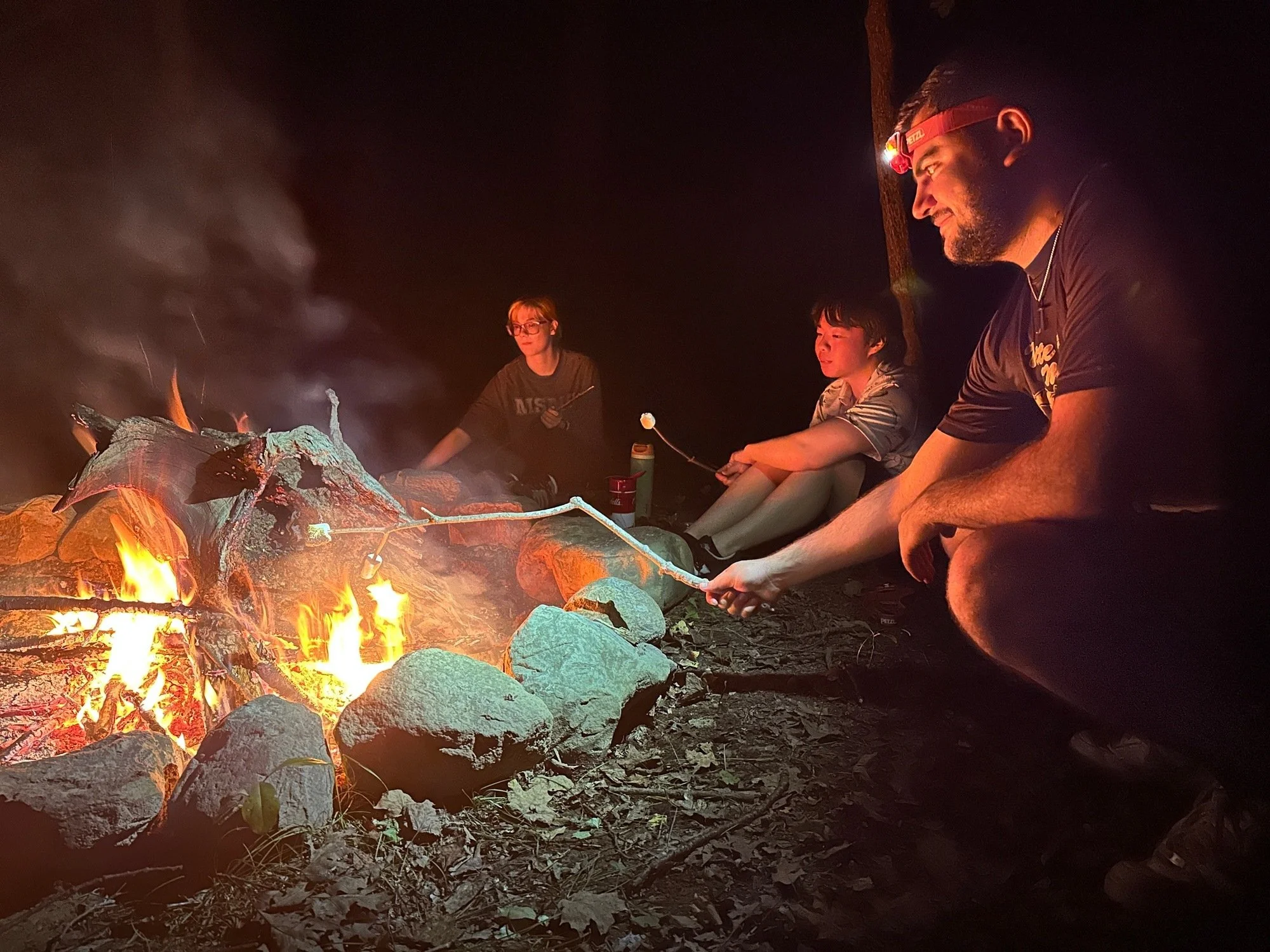   Three Mount Saint Mary College Biology students take a break and roast marshmallows around the campfire during a recent camping trip that focused on experiential learning and the natural sciences. Left to right: Aleksandra Belugin, Jae Lembo, and W
