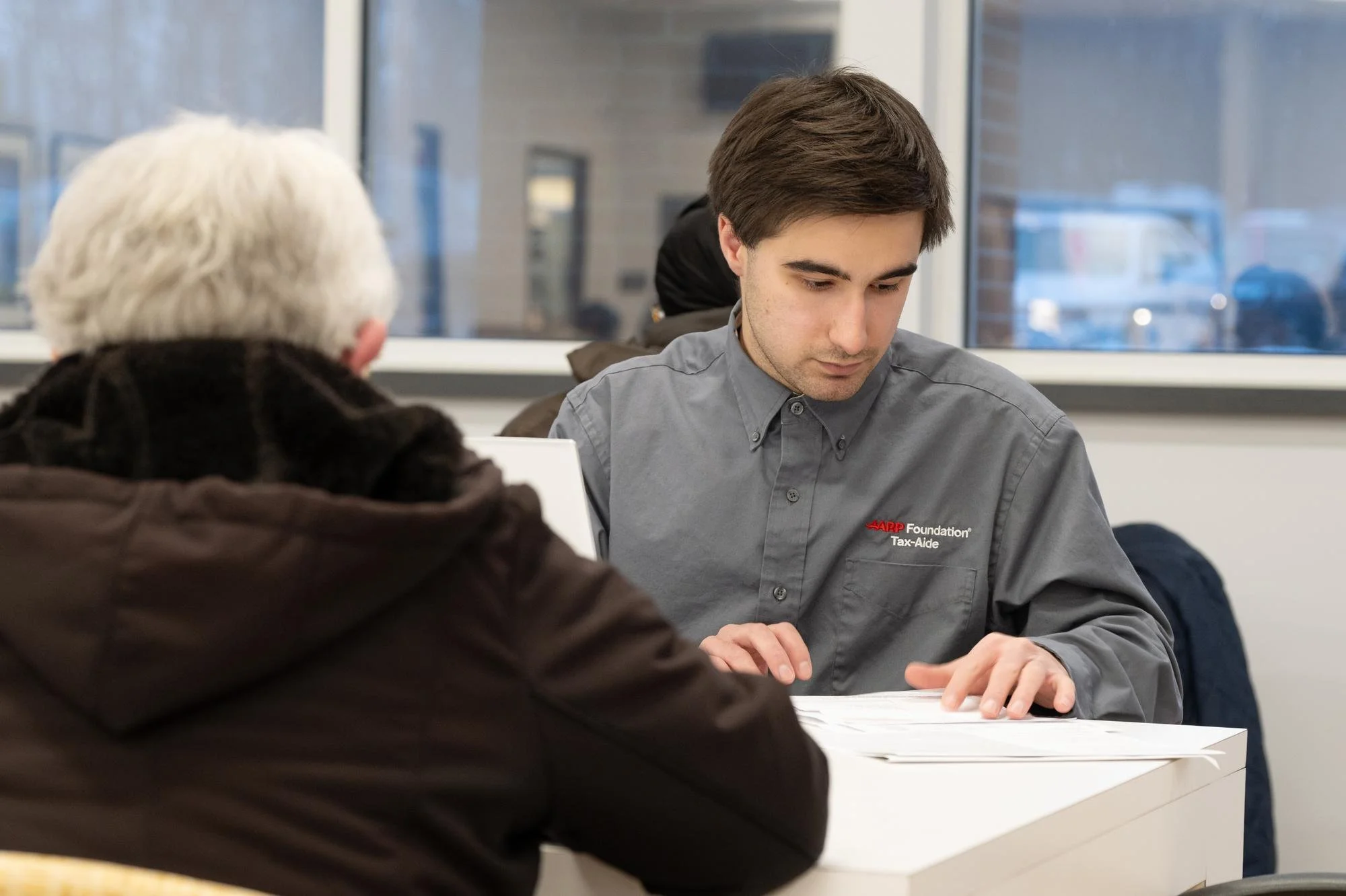   Nicholas Clarino, an accounting major, reviews tax documentation with a client. Clarino is one of several students volunteering their skills to provide free tax services to the community this season.  