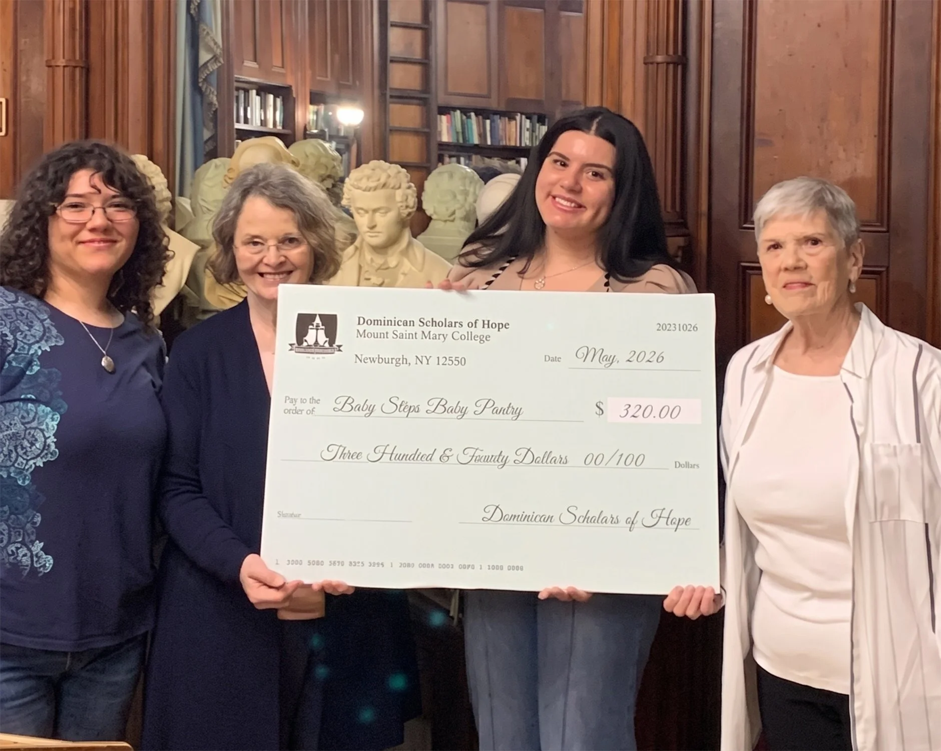 Students with the Dominican Scholars of Hope hold a check for Baby Steps Baby Pantry with members of the organization.