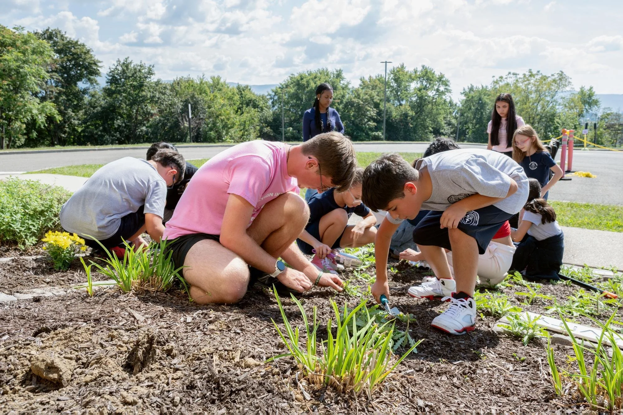   Mount freshmen and Bishop Dunn Memorial School students work together to plant flowers in the Sensory Garden on the Mount campus as part of the college's First-Year Experience (FYE) program.  