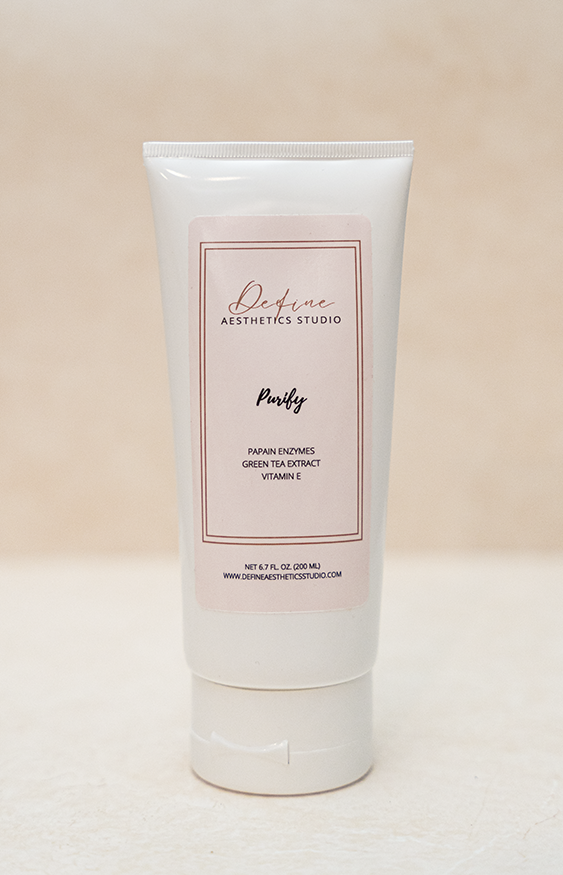A white tube of Define Aesthetics Studio Purify skincare product on a light surface with a beige background.