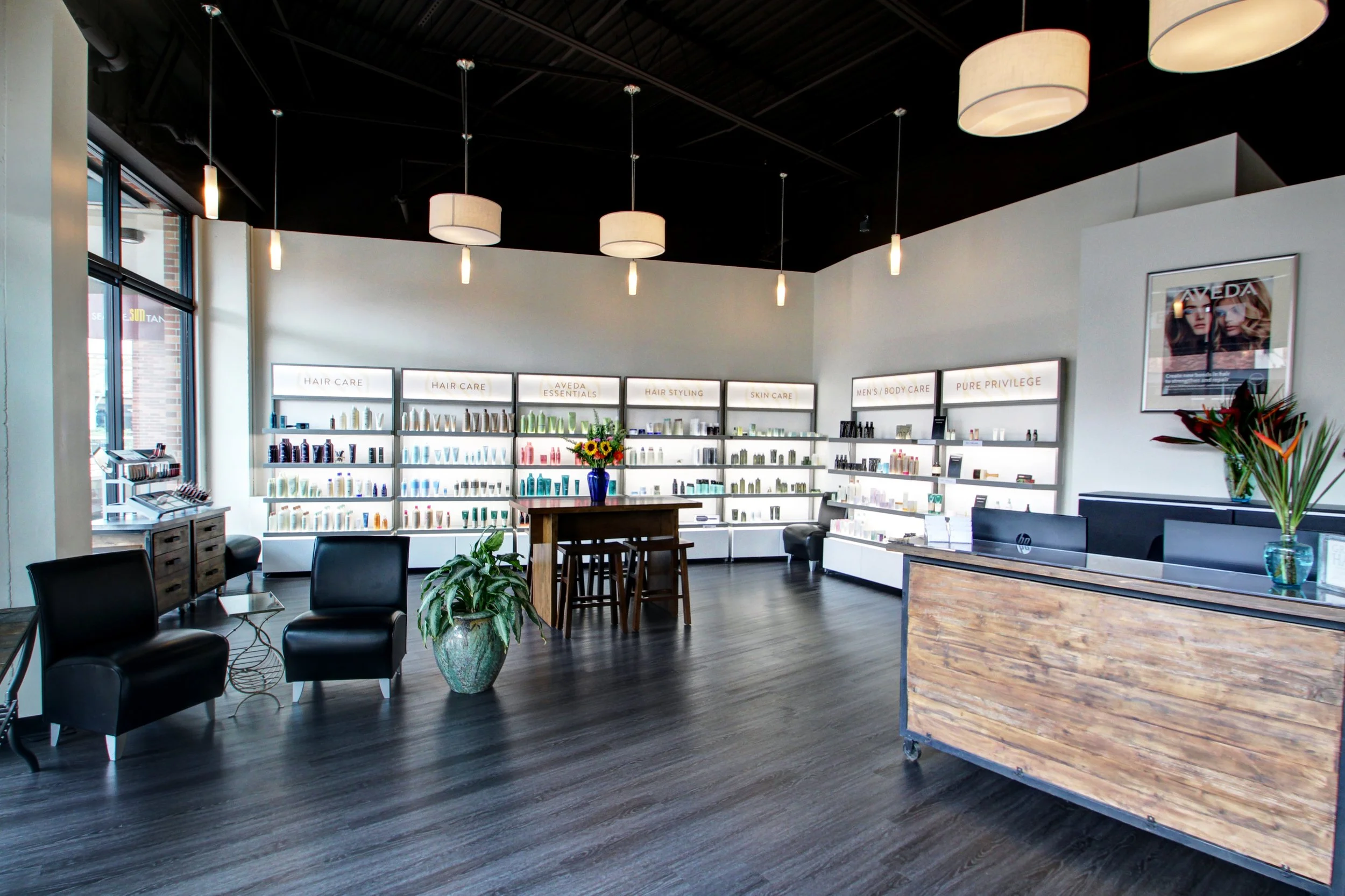Interior of a modern retail store, displaying shelves with skincare and beauty products, a reception desk, seating area with chairs and plants, and decorative lighting fixtures