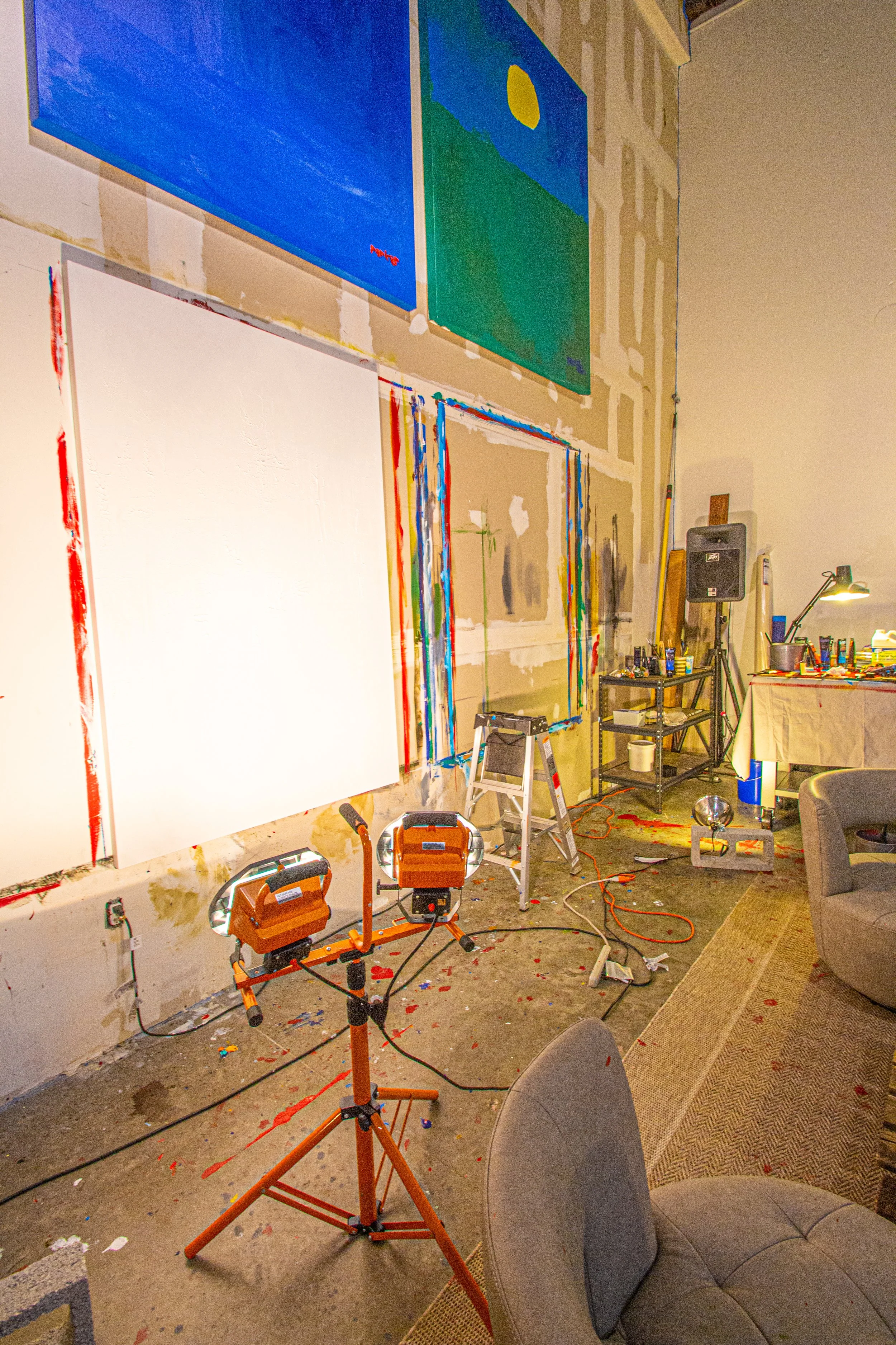 An art studio with paintings, painting supplies, and studio lights.