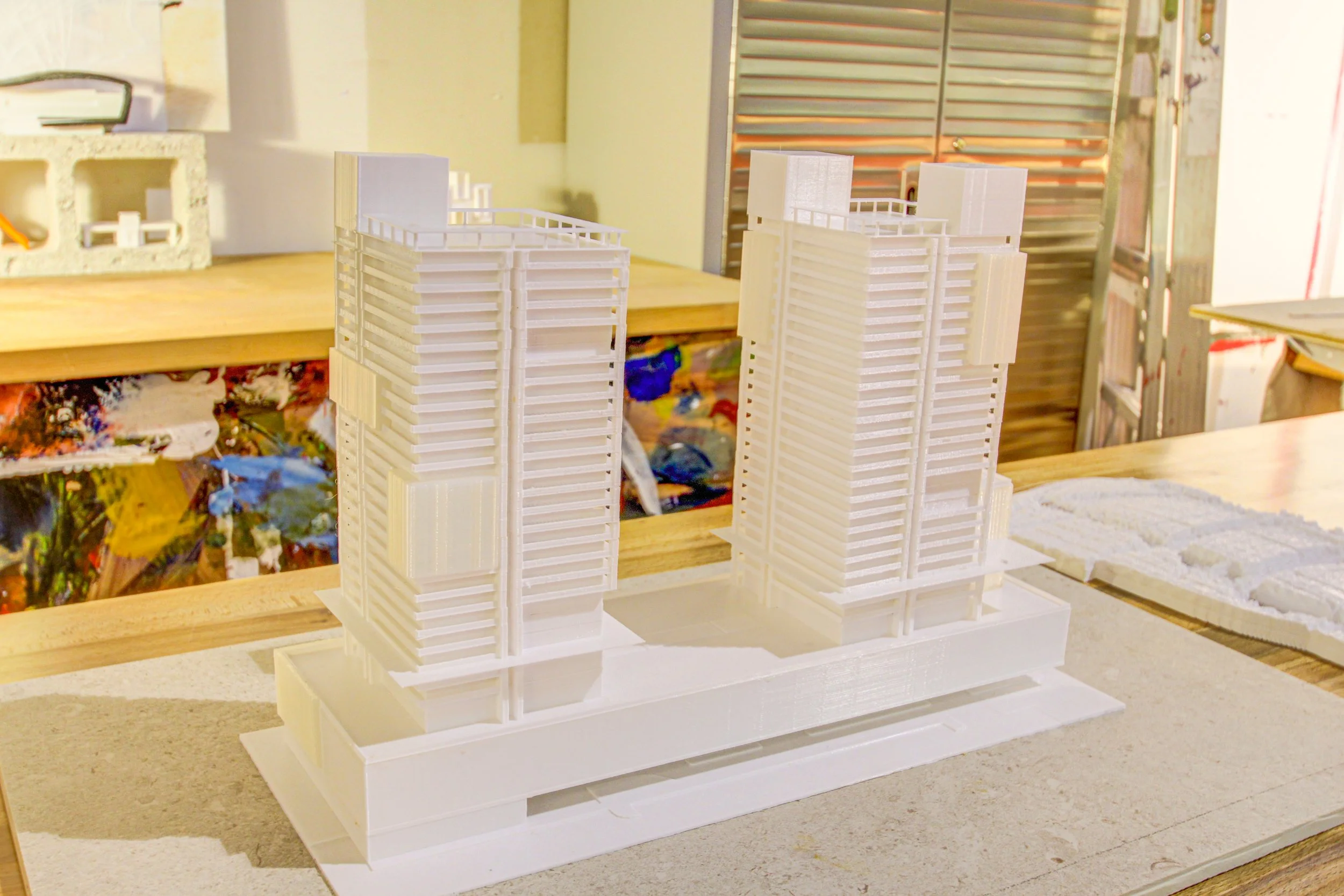 Architectural model of two modern high-rise buildings on a table in a workshop.