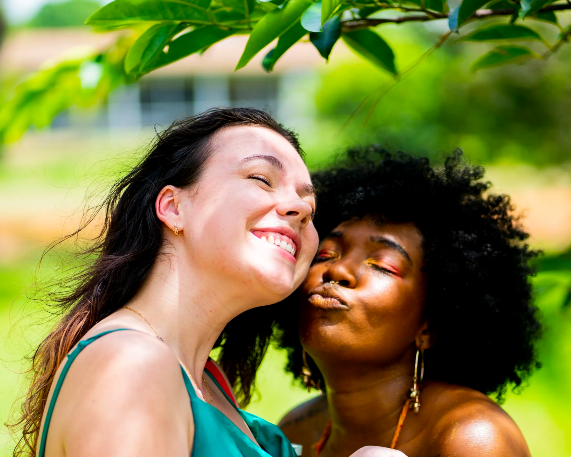 Smiling women of different ethnicities celebrating outdoors in a lush green park.